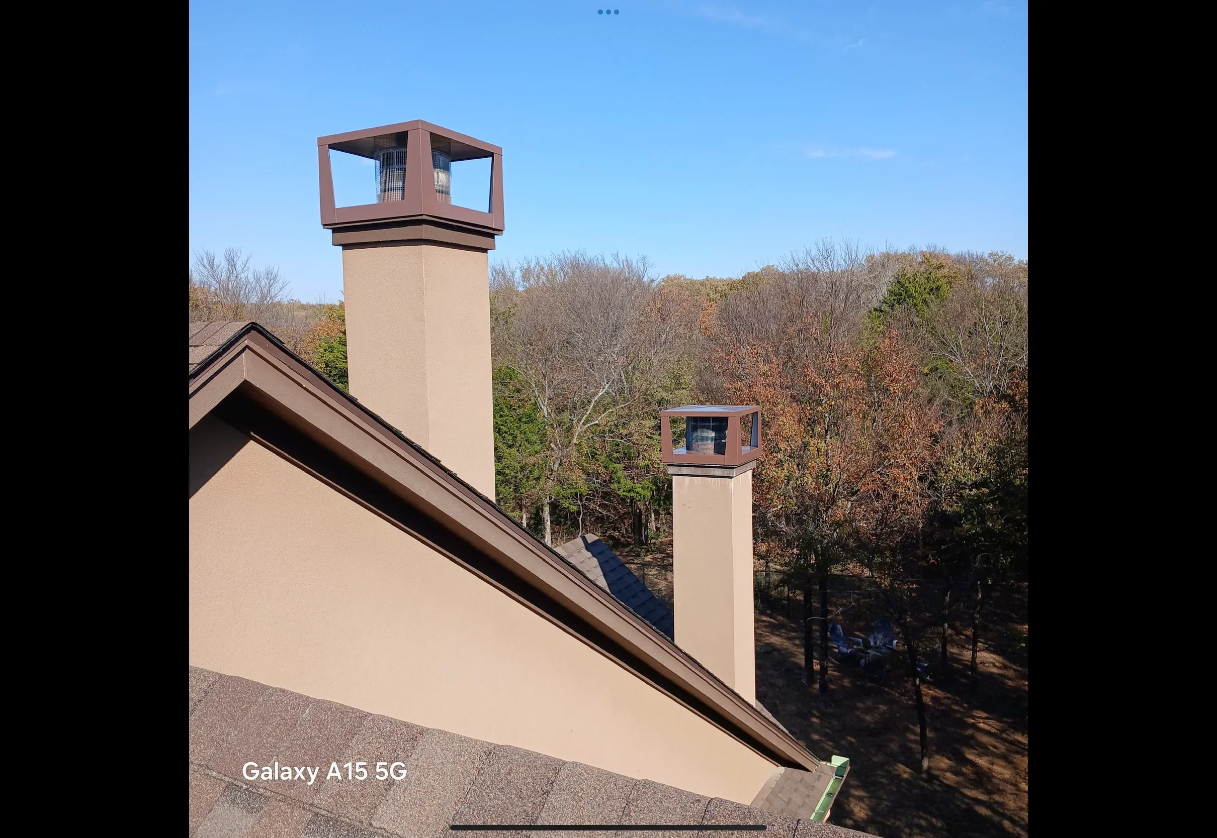 Metal roof with standing seam and two custom metal chimney caps with copper-colored trim boxes