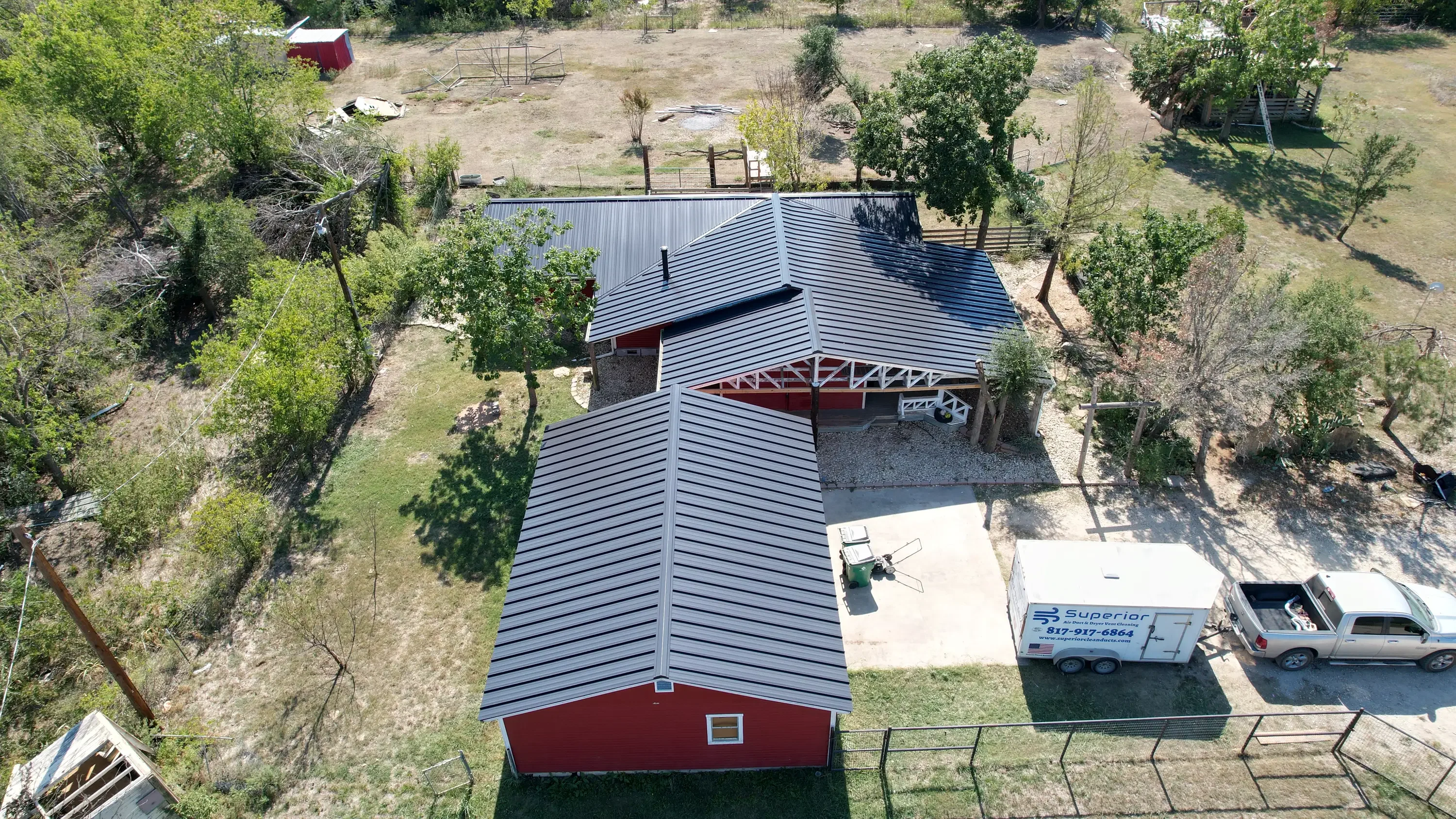 Dark gray standing seam metal roof on red barn with multiple peaks and angles