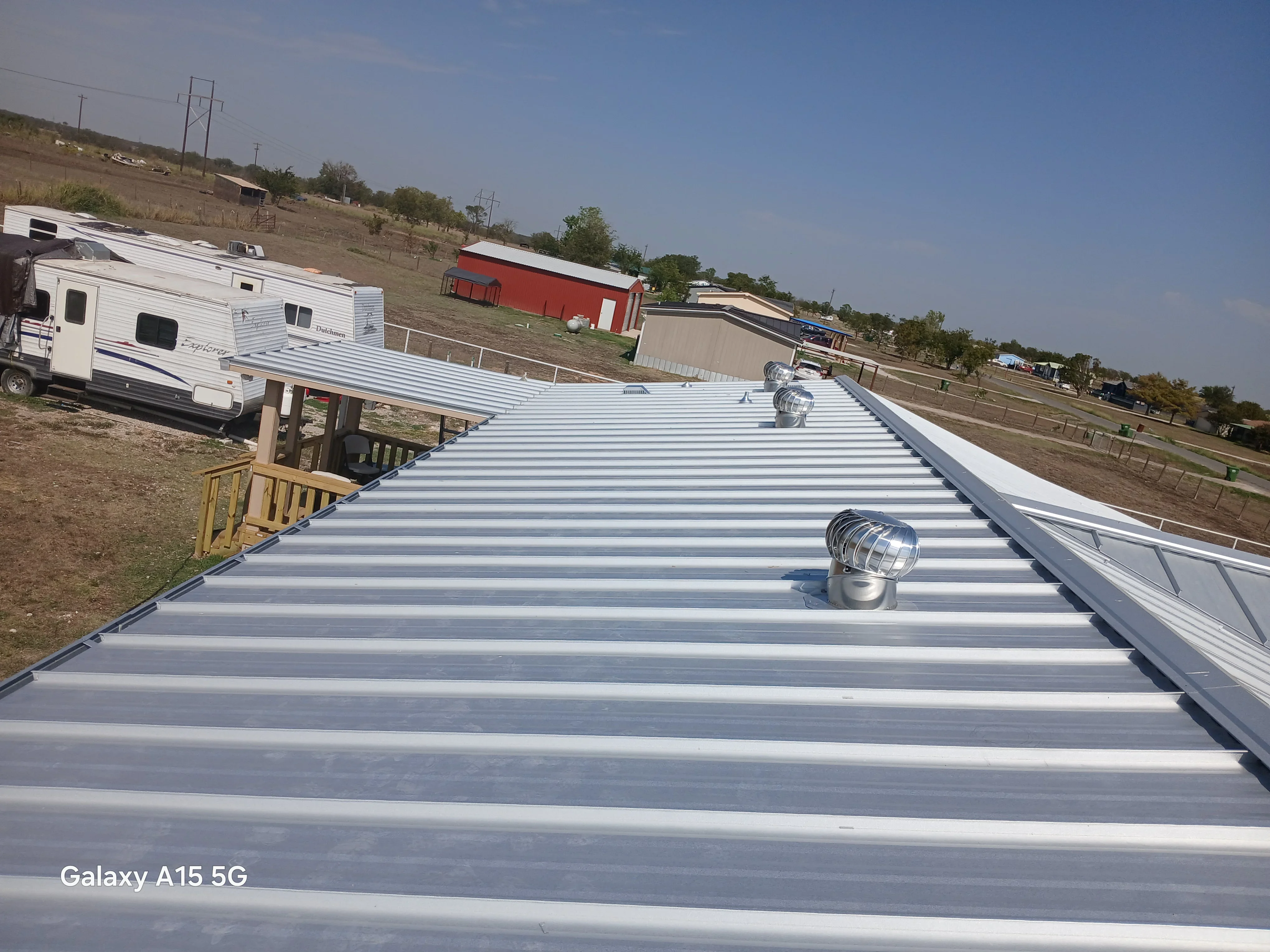 Standing seam metal roof with corrugated panels and roof vents installed on agricultural building