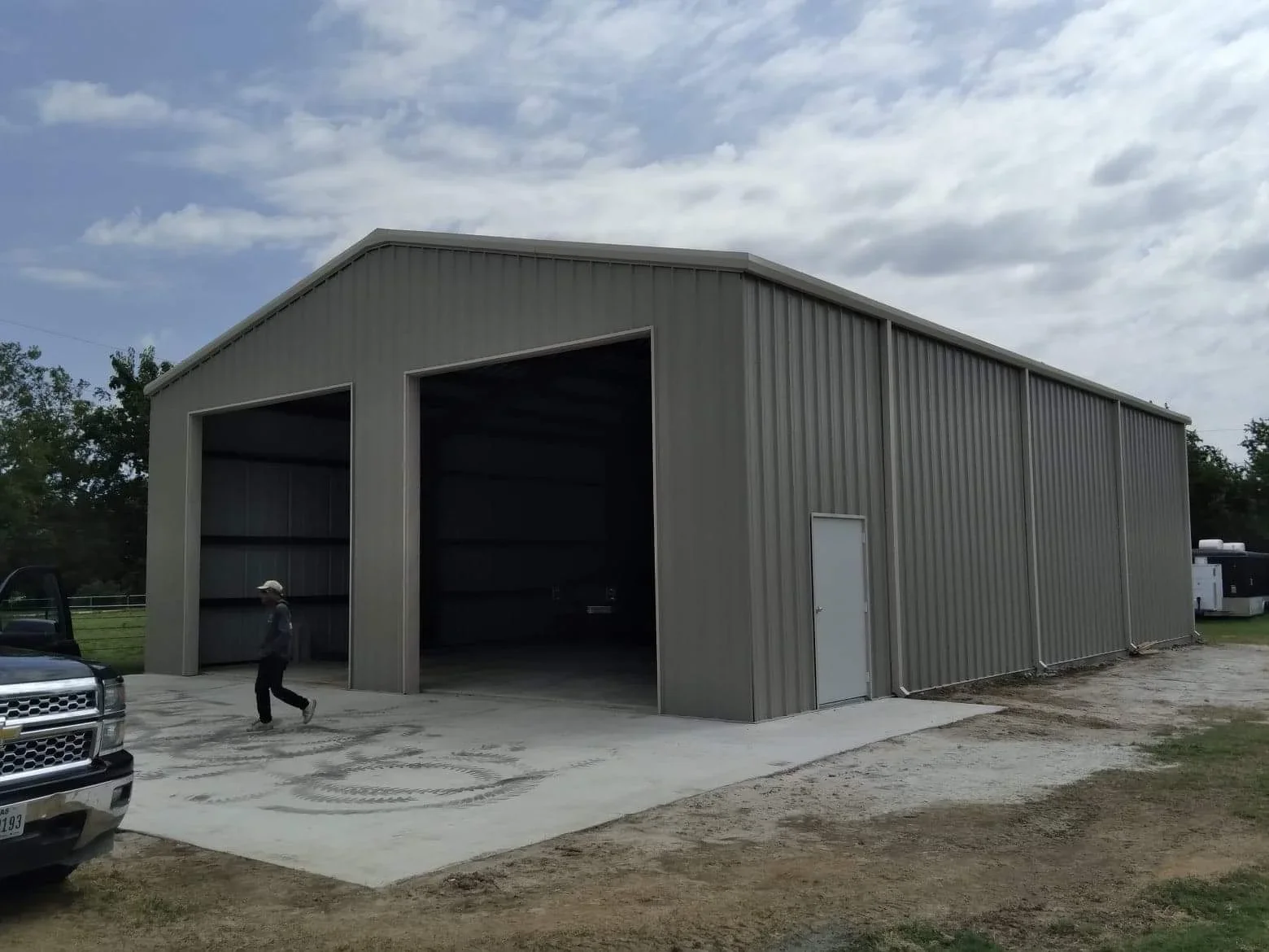 Charcoal gray metal building with corrugated steel siding, gabled roof, and dual overhead bay doors