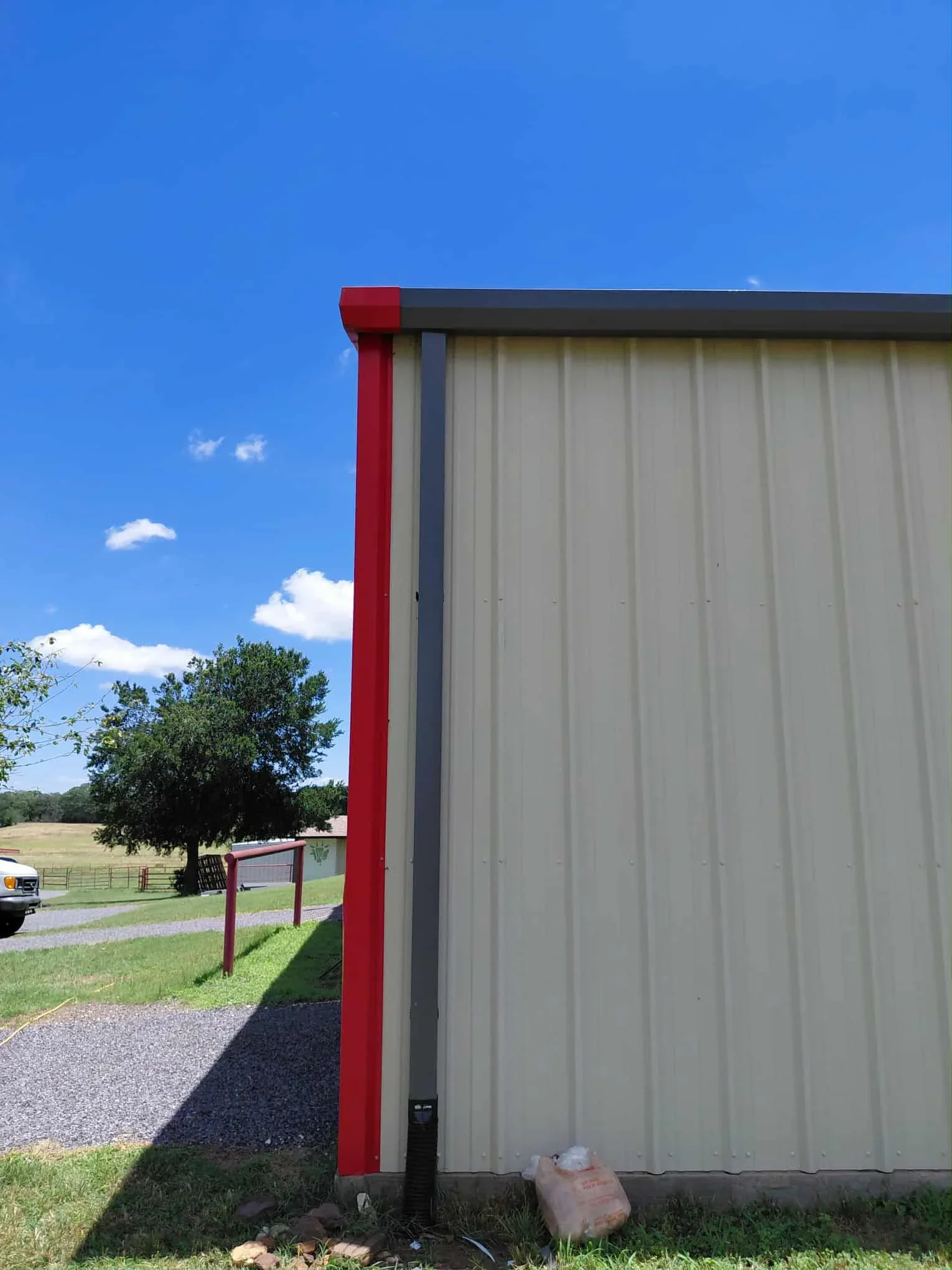 Standing seam metal roof with red columns and corrugated metal wall panels on agricultural building