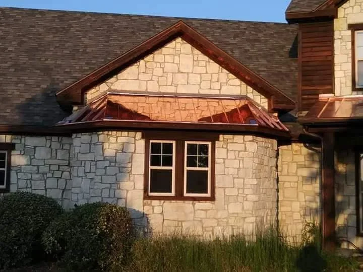 Copper standing seam metal roof on stone gable addition with matching copper gutters