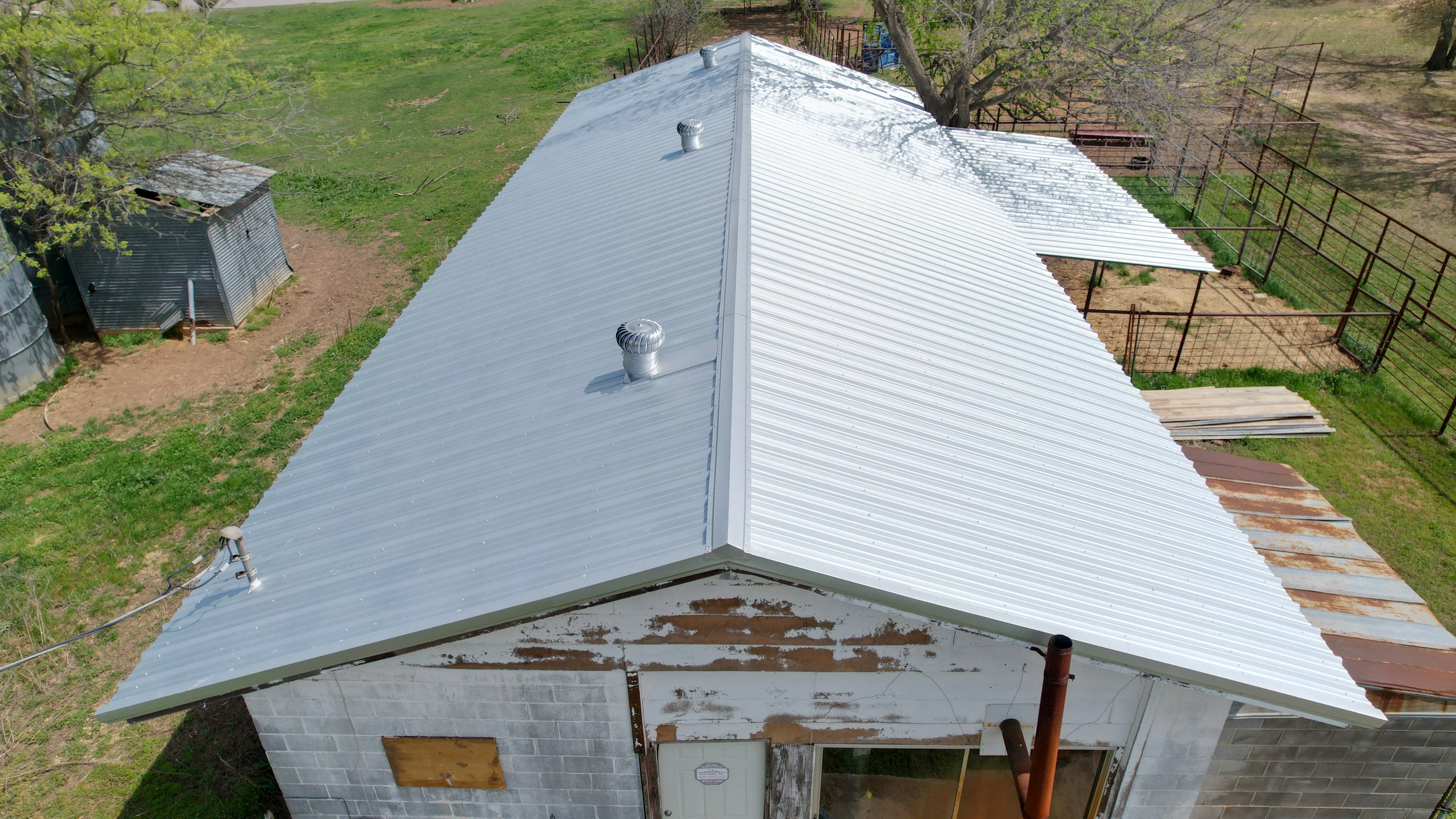 Light gray standing seam metal roof with vents on residential building