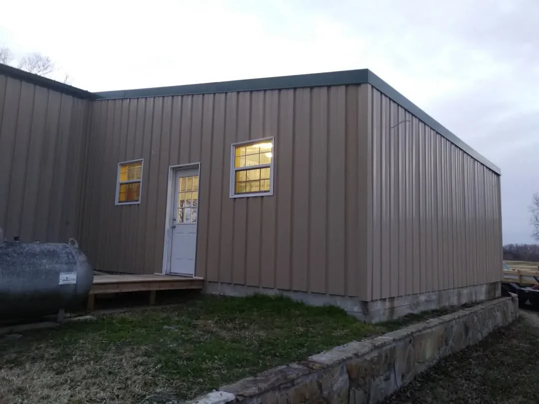 Metal building with vertical corrugated steel siding and standing seam roof