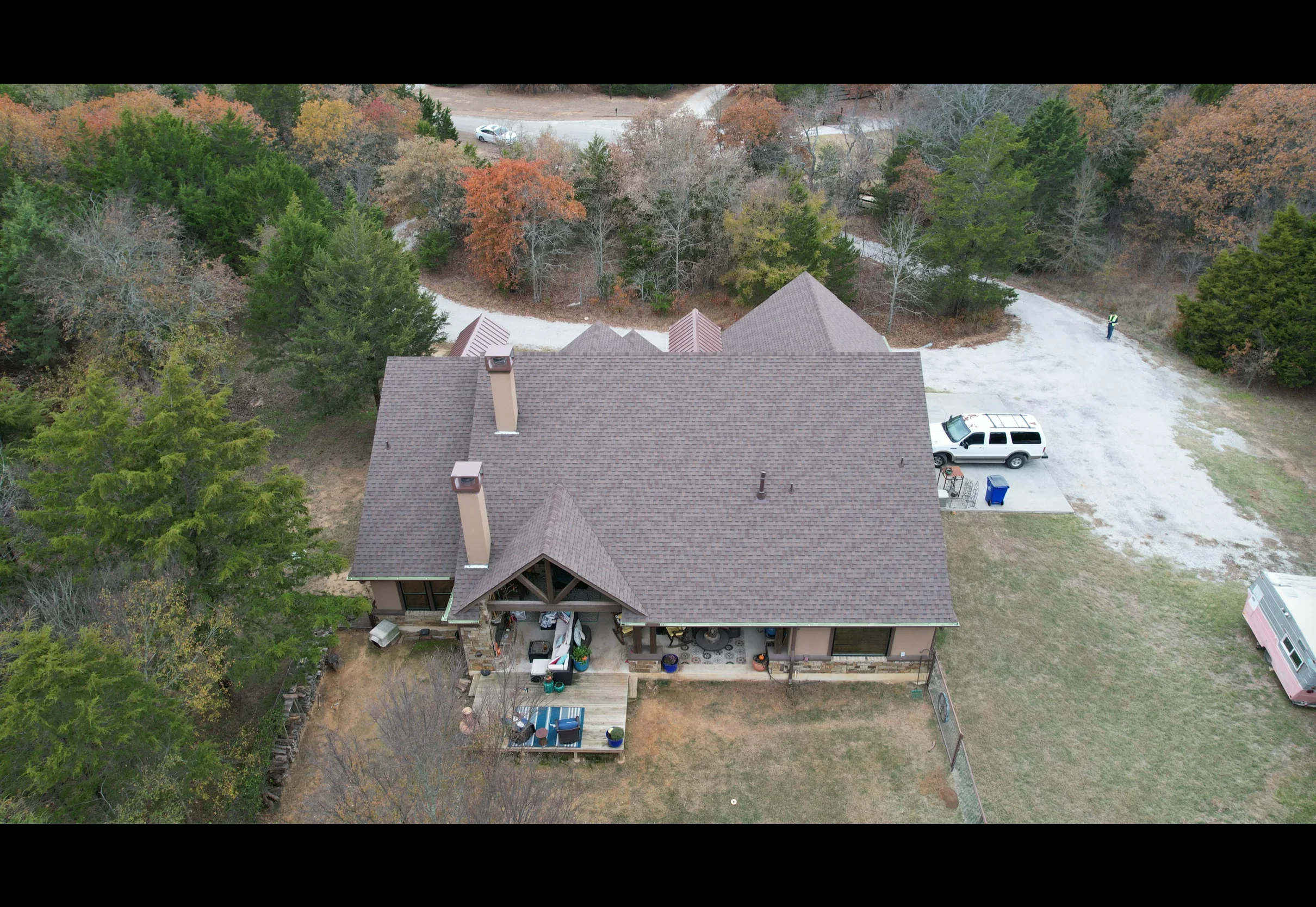Gray metal shingle roof with multiple gables and brown metal flashing on residential home