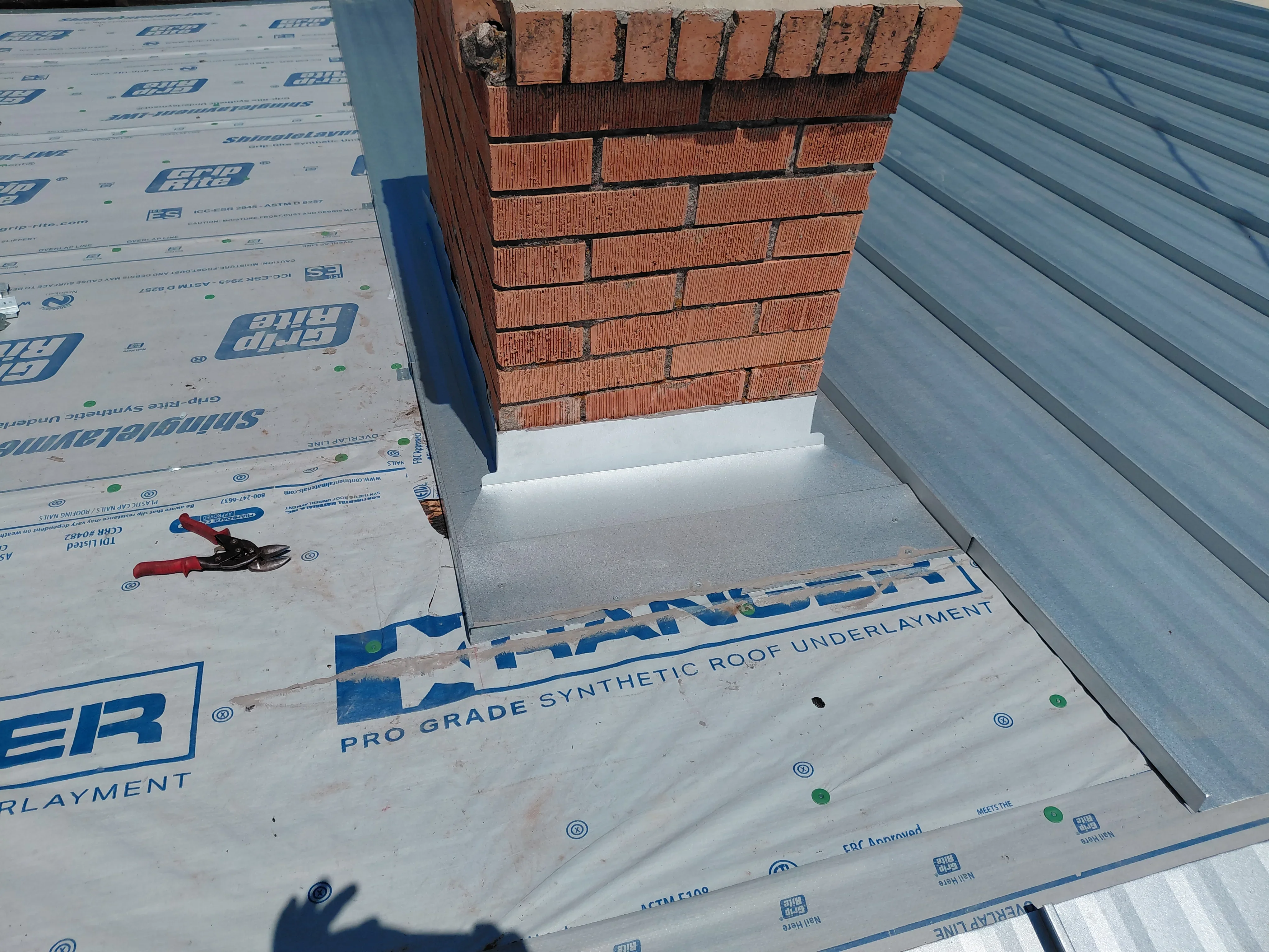 Brick chimney with synthetic roof underlayment and fasteners during installation