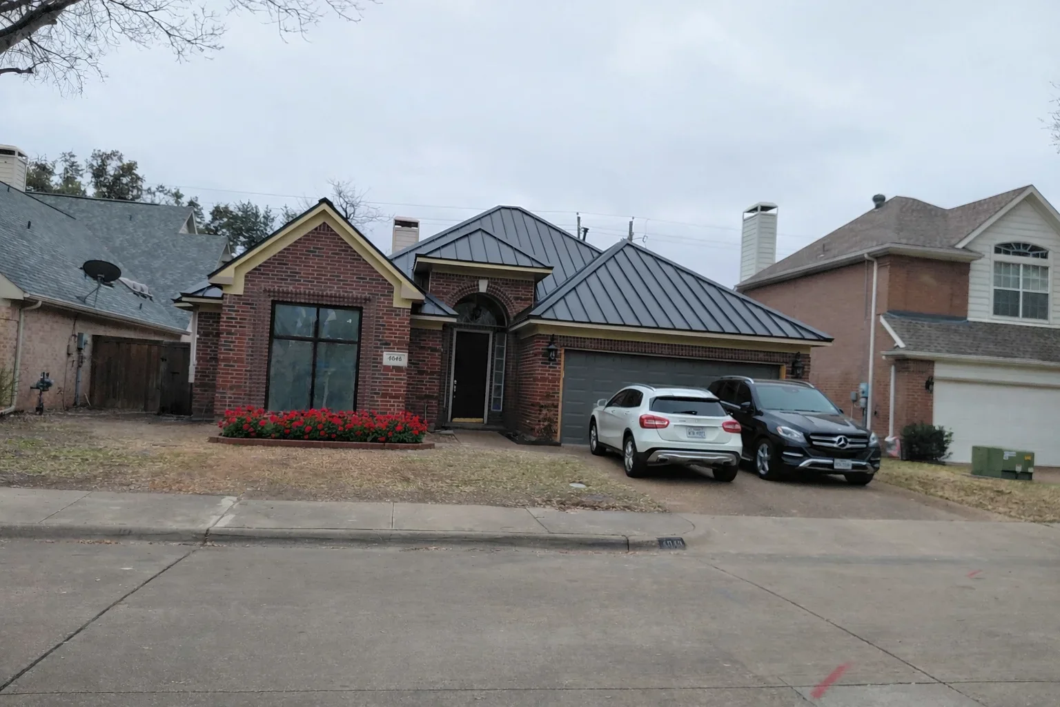 Standing seam metal roof on brick home with gable peaks and multiple roof planes