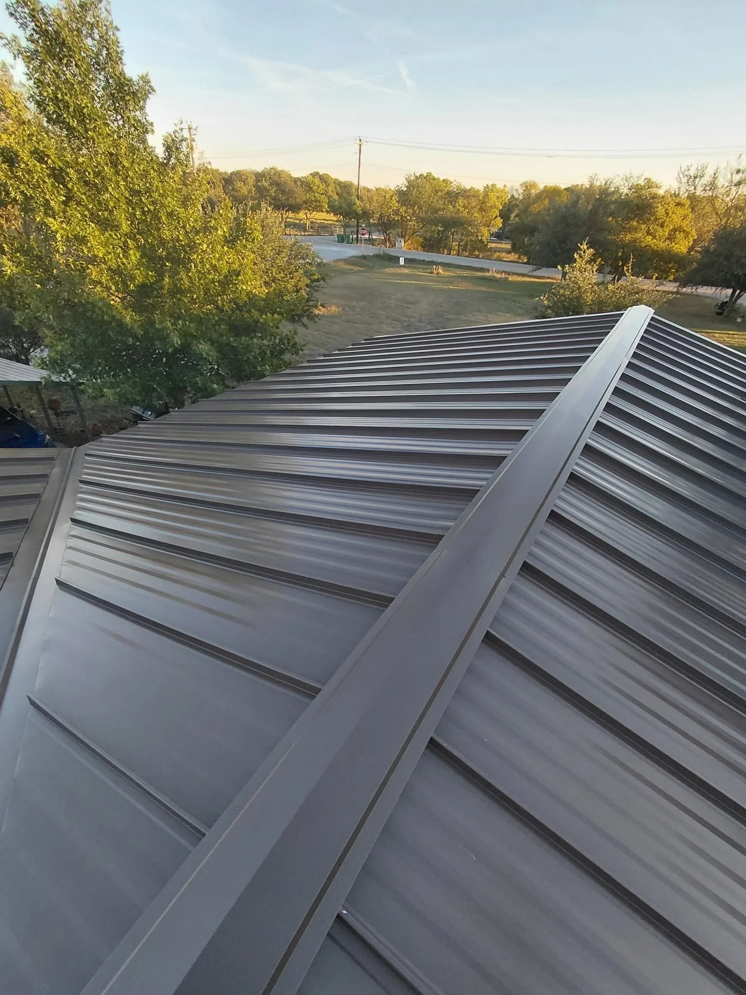 Standing seam metal roof with gray panels and raised ribs installed on residential structure