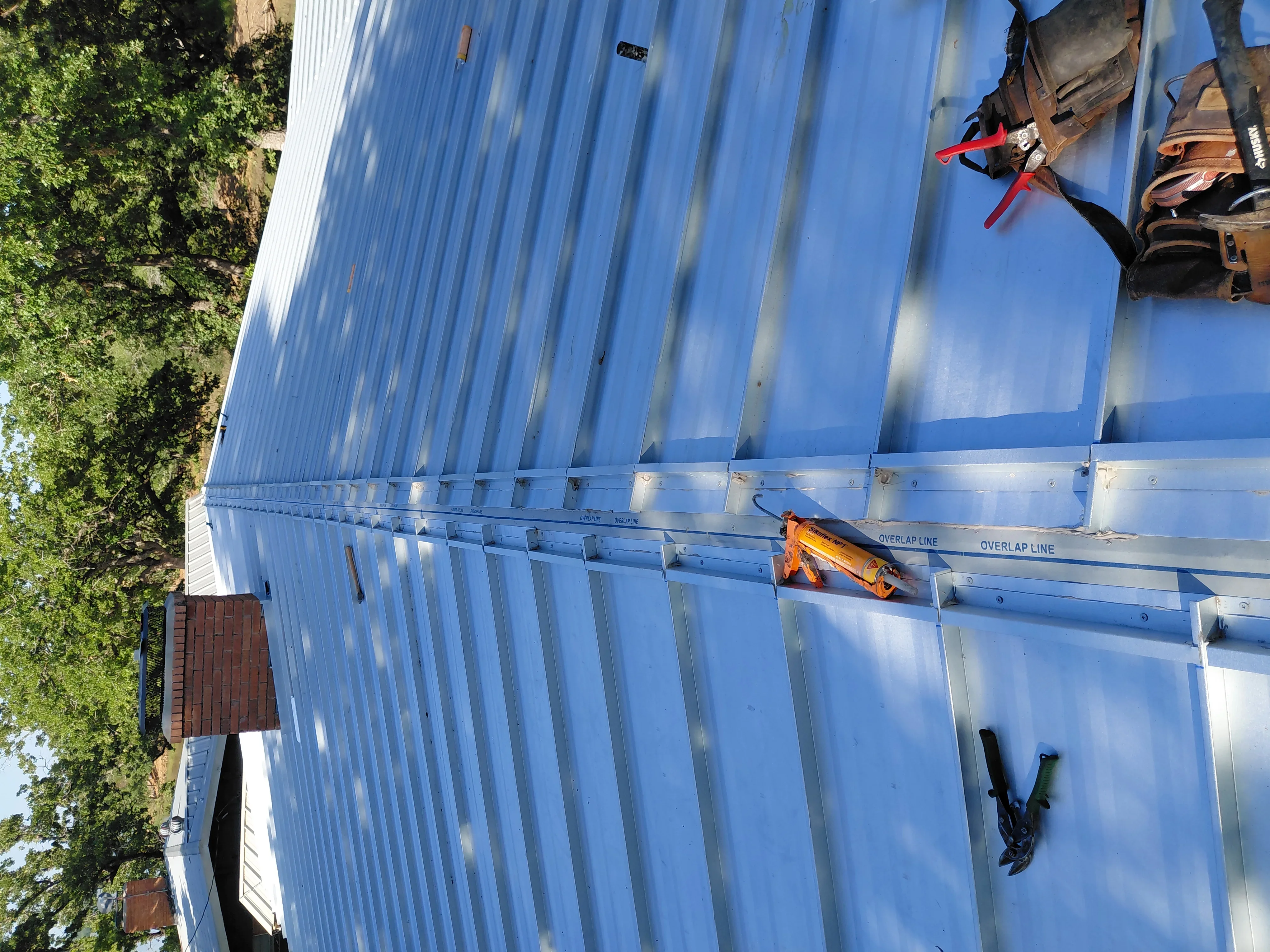 Corrugated metal roof panels installed with overlap lines and fasteners on residential structure