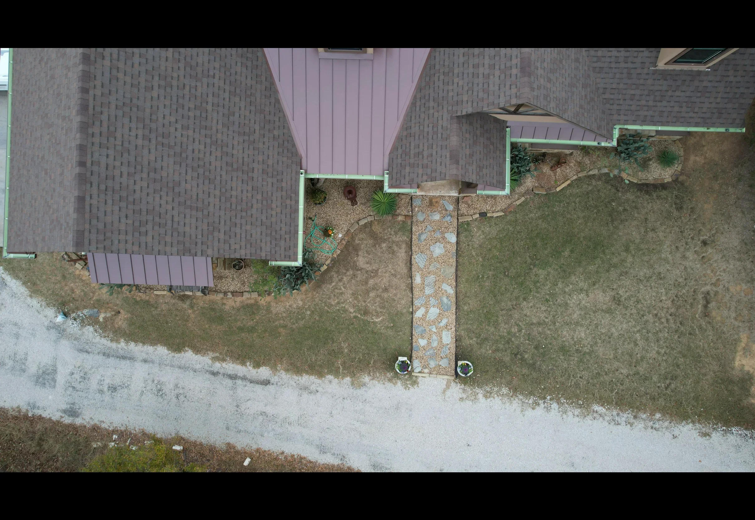 Aerial view of standing seam metal roof installation on residential brick home with mauve finish