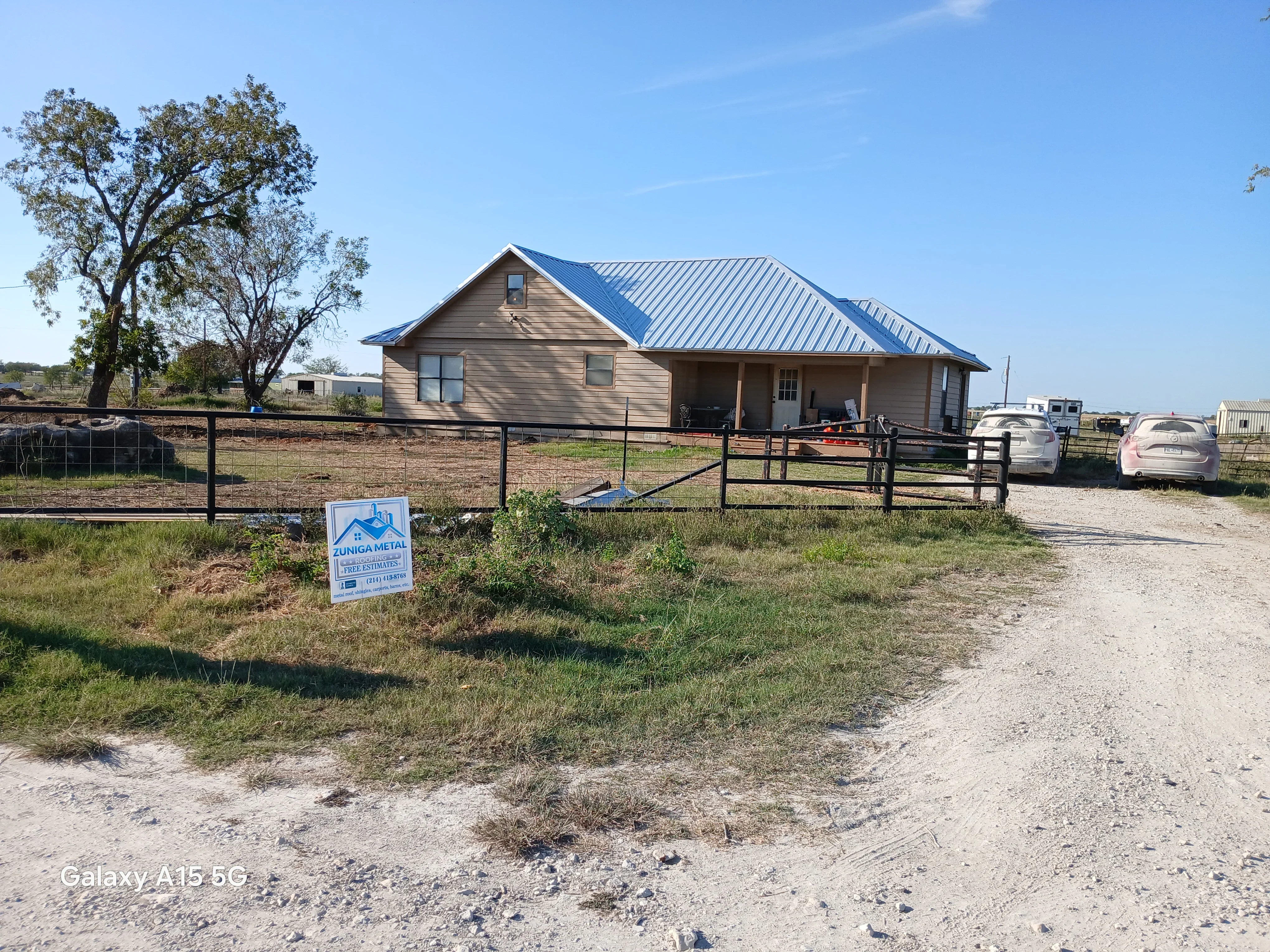 Standing seam metal roof installation in blue on residential home with composite siding