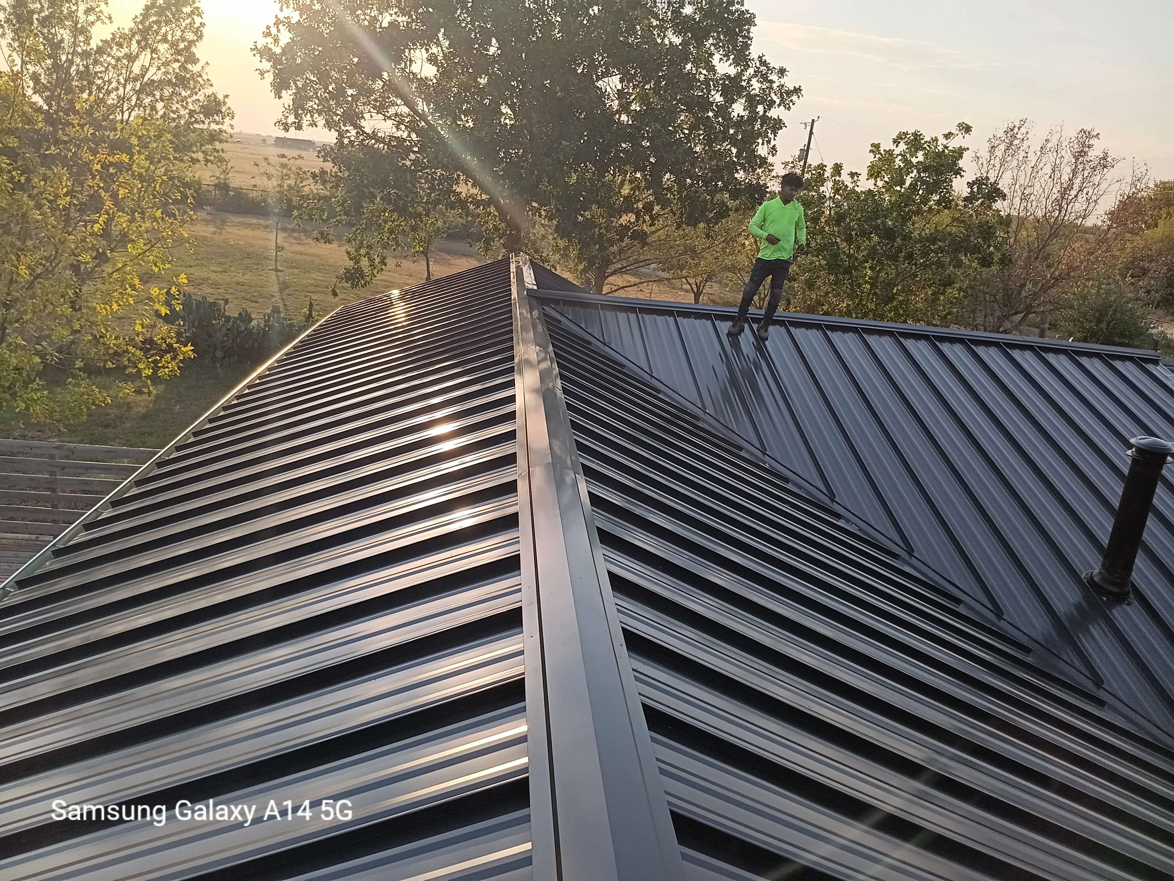 Standing seam metal roof with dark finish panels and ridge cap installation