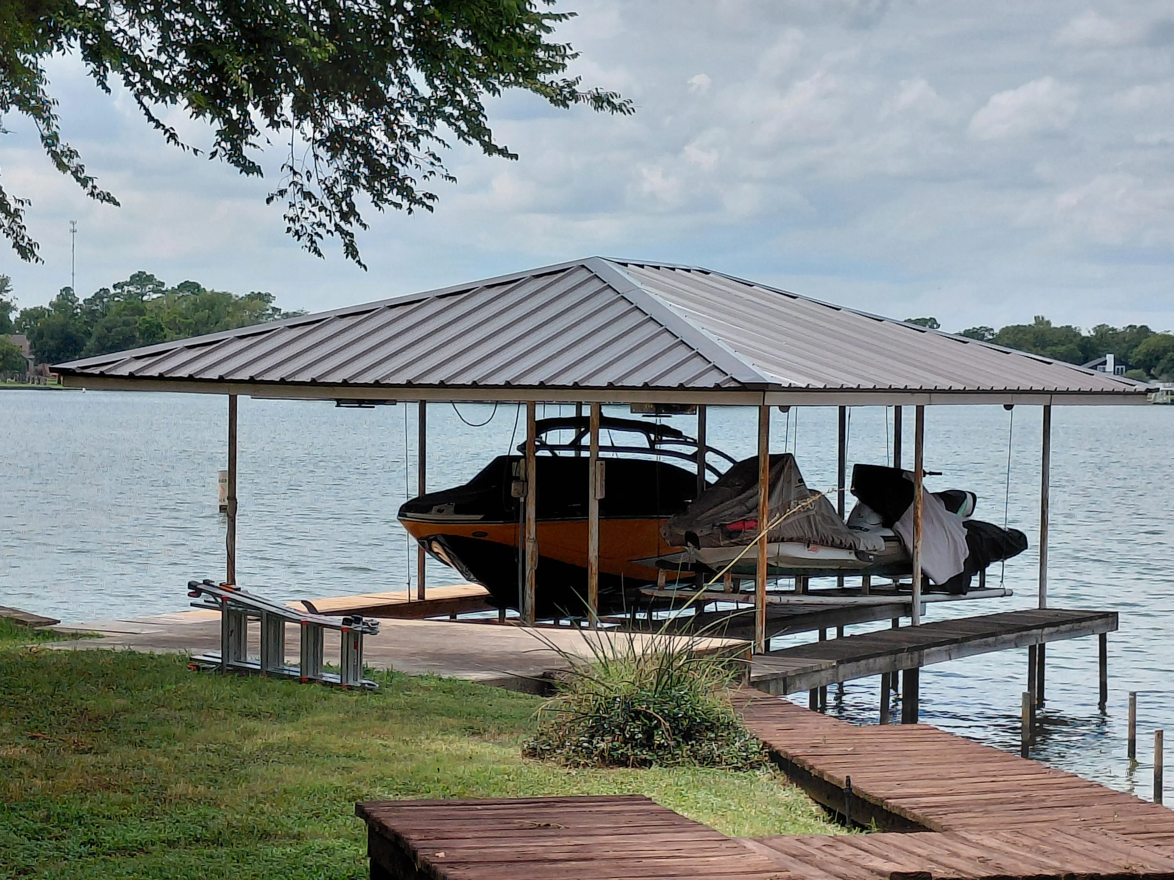 Standing seam metal roof over waterfront boat dock with wooden deck and support structure