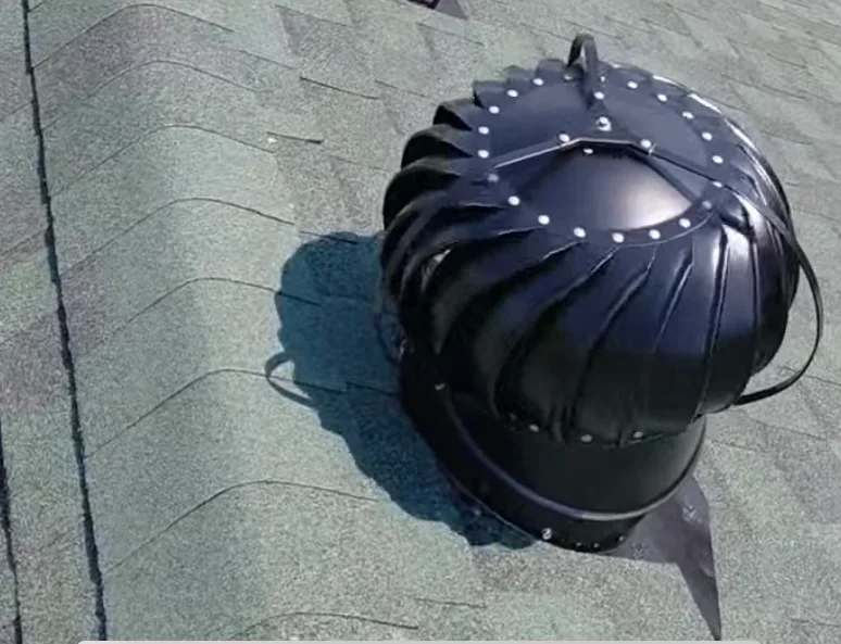 Black metal turbine roof vent with studded dome installed on asphalt shingle roof