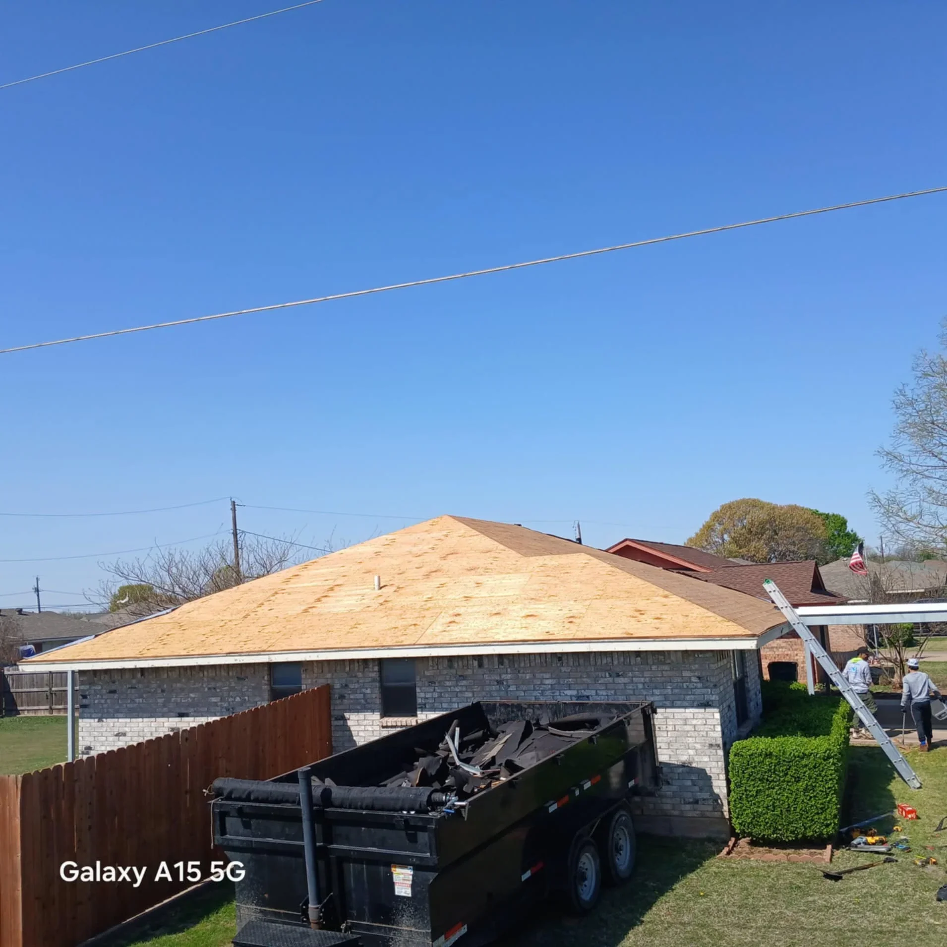 New asphalt shingle roof installation on brick residential home with ladder and debris removal