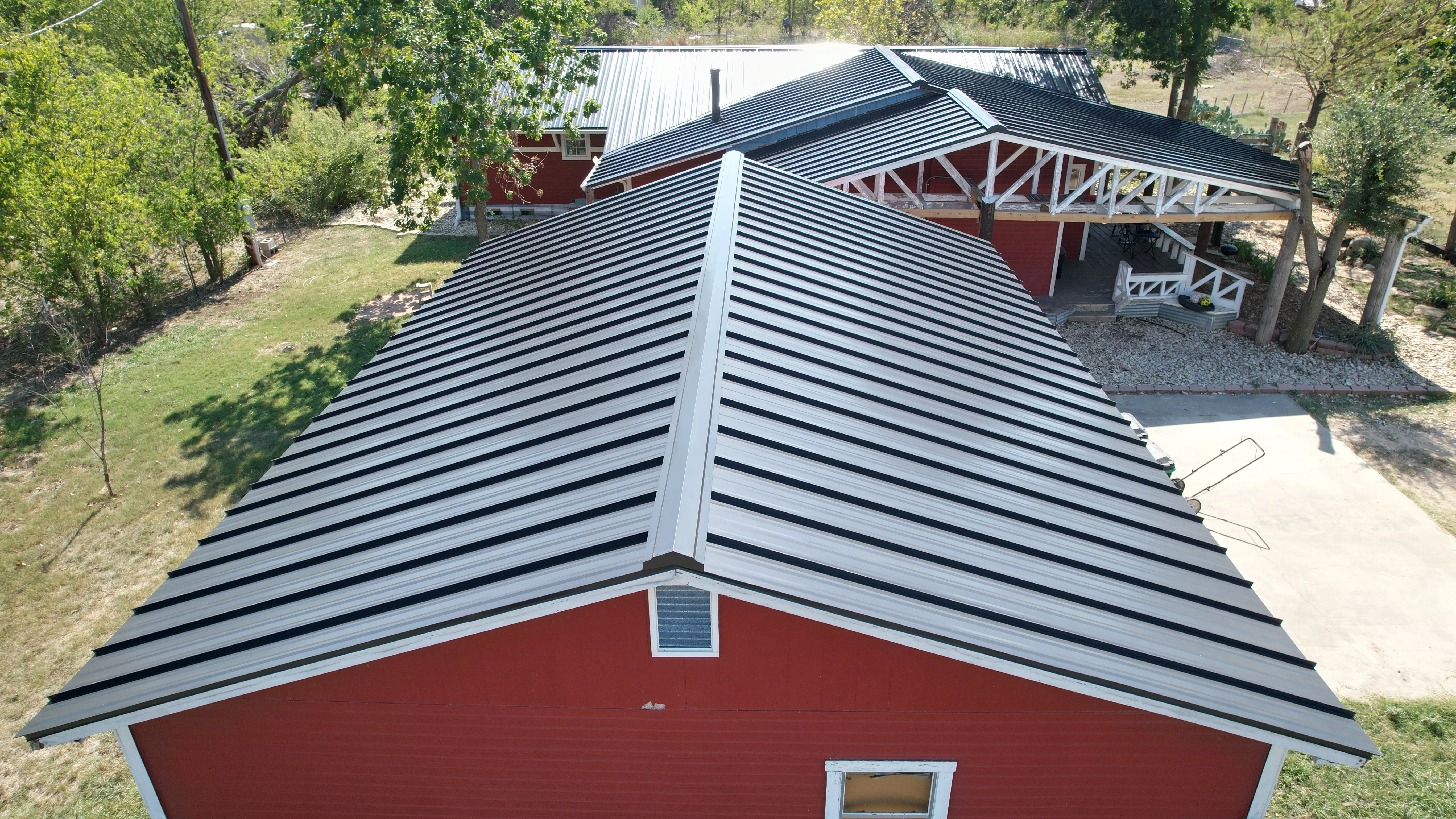 Dark gray standing seam metal roof with white trim on red barn building