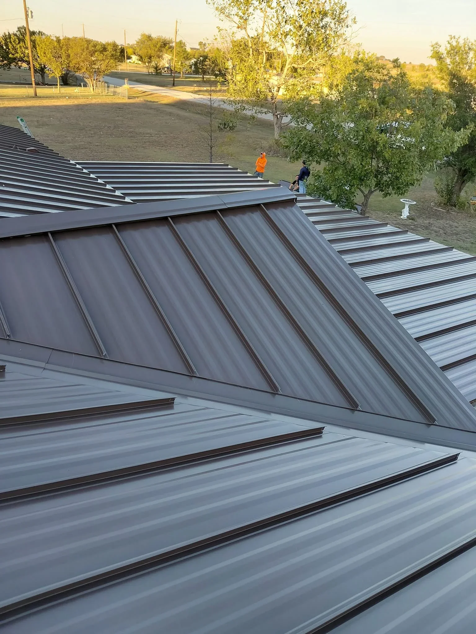 Standing seam metal roof with gray panels and raised seams during installation