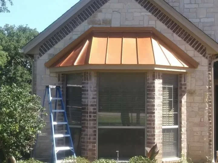 Copper standing seam awning with vertical seams installed over brick home entrance