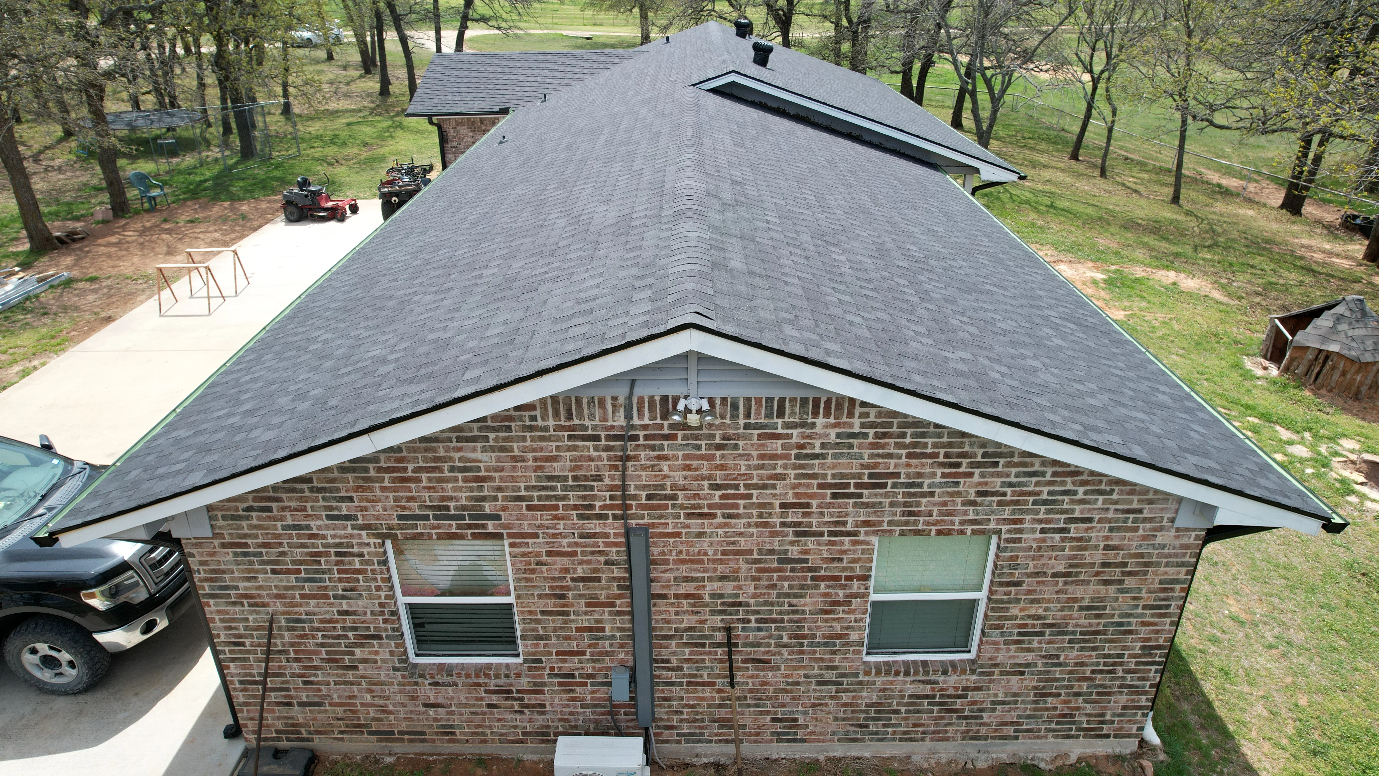 Gray asphalt shingle roof on brick home with gable design and ridge vents