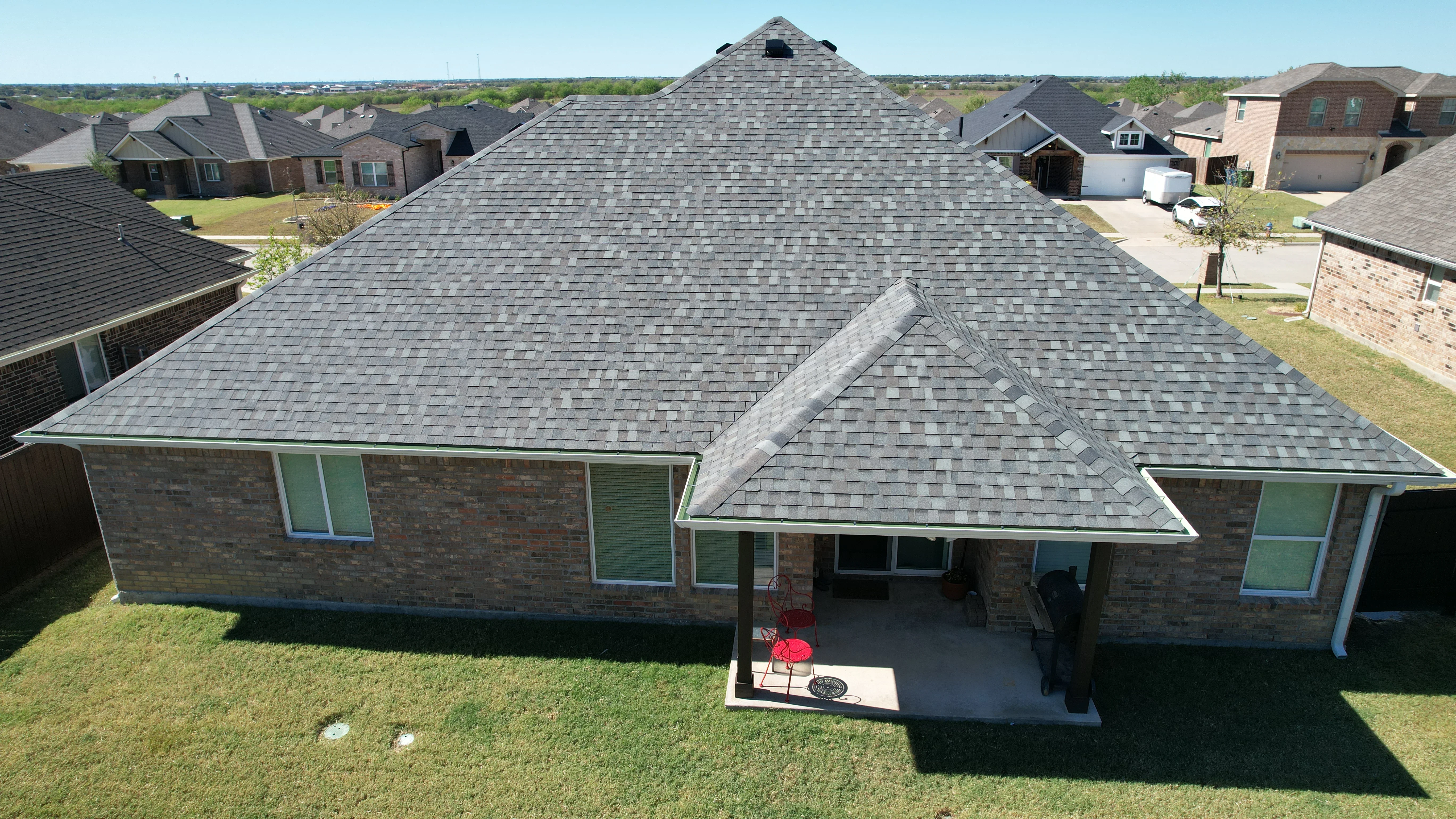 Gray asphalt shingle roof on brick home with multiple peaks and dormers