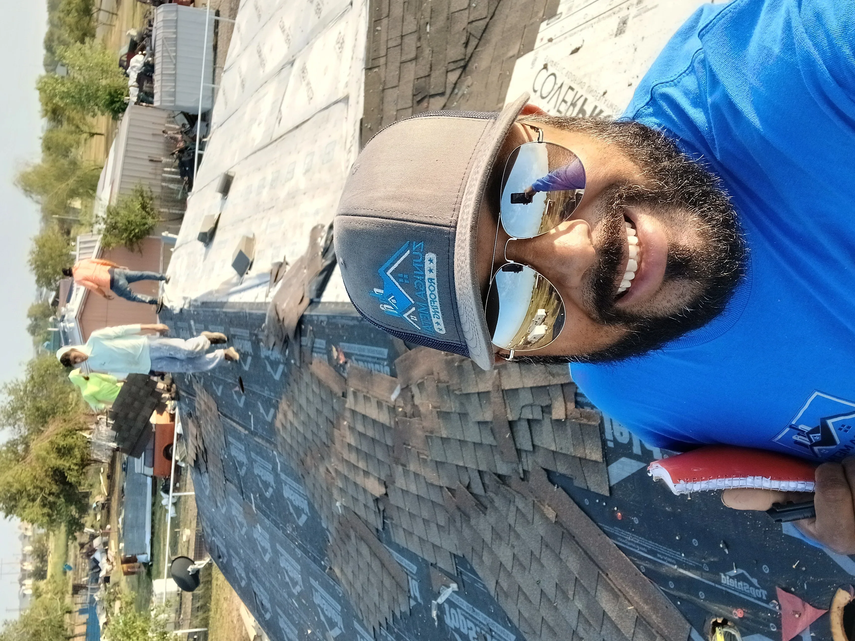 Roofer installing dark gray asphalt shingles on residential roof with proper overlap and fastening