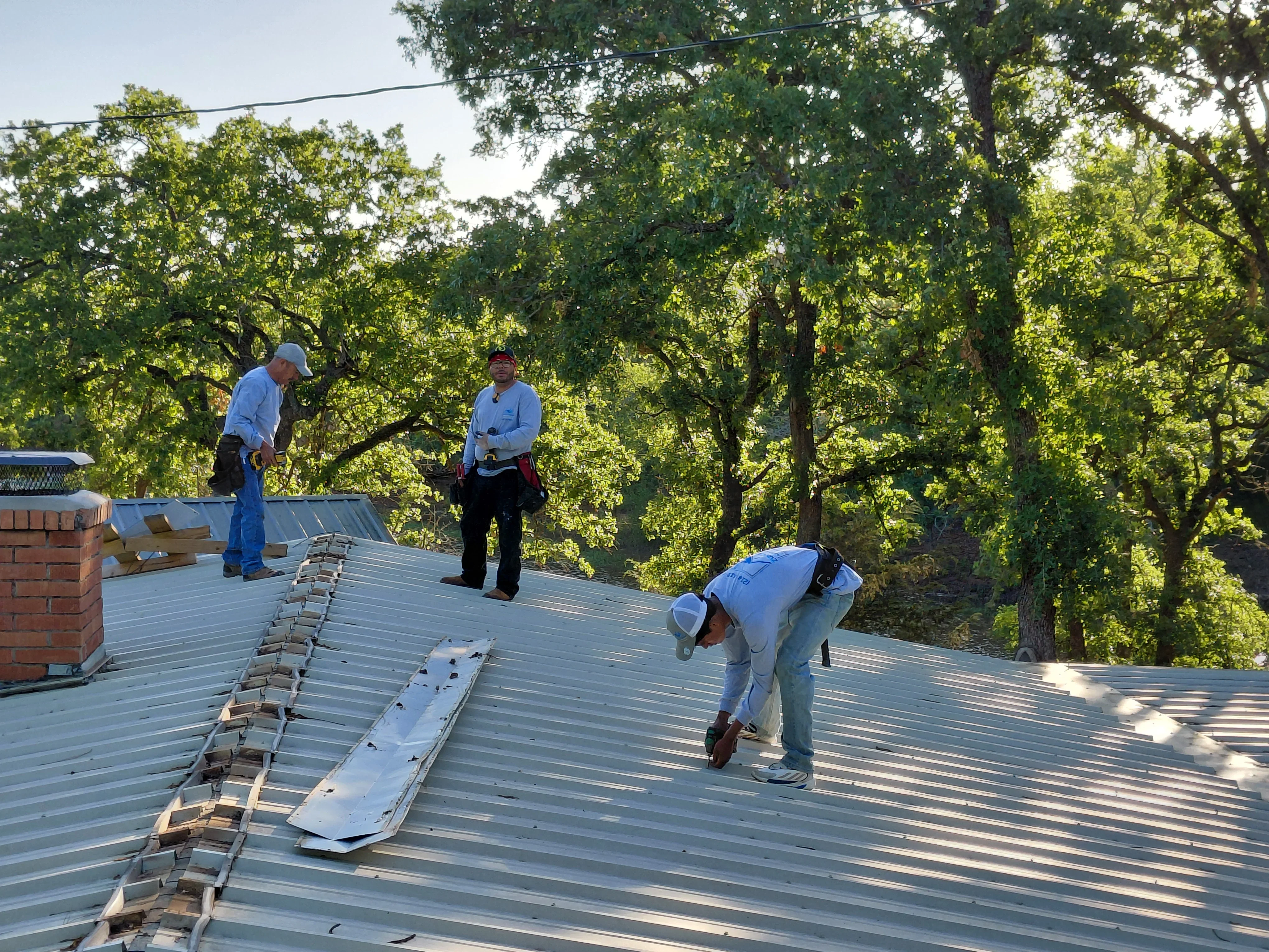 Crew installing standing seam metal roof panels with proper fastening and alignment