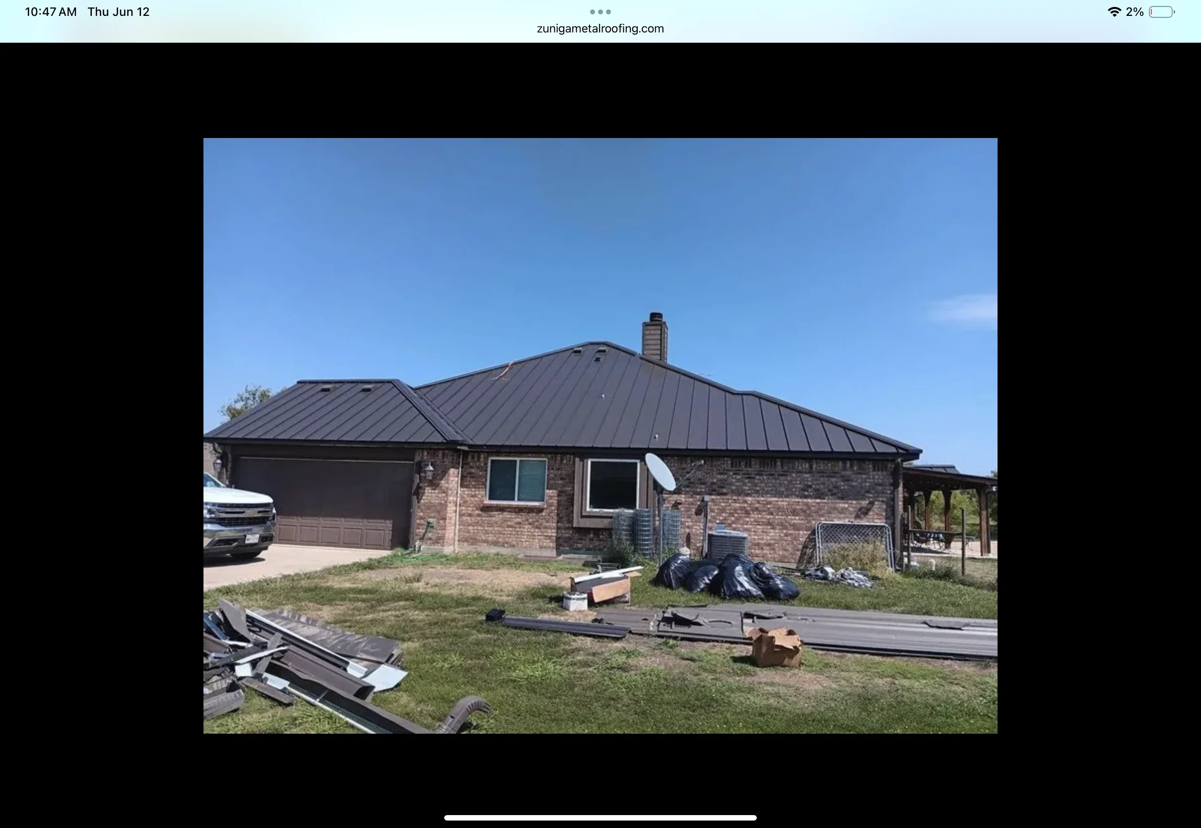 Dark gray standing seam metal roof installed on brick home with chimney and multiple roof planes