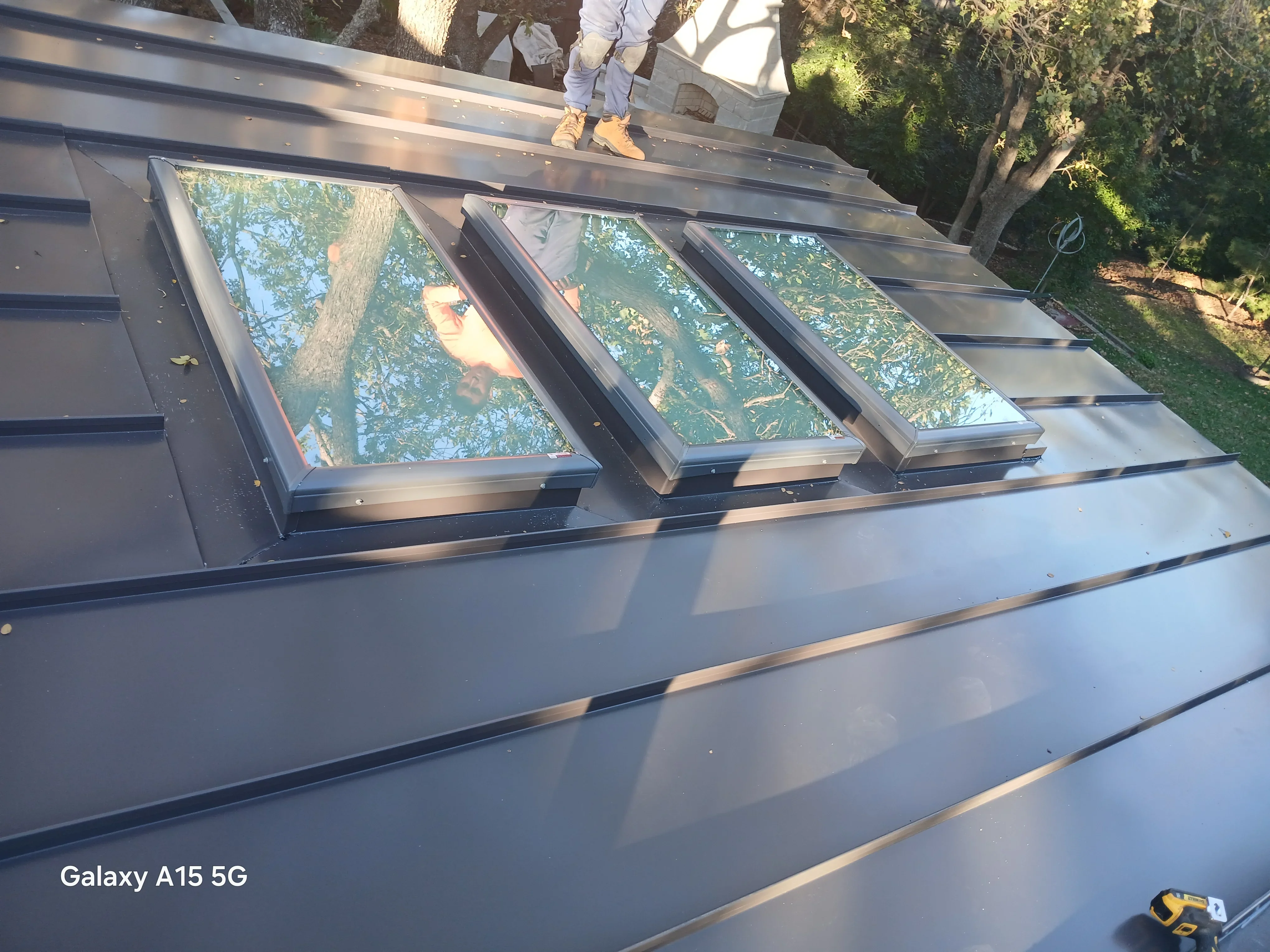 Standing seam metal roof with three aluminum-framed skylights installed in sequence