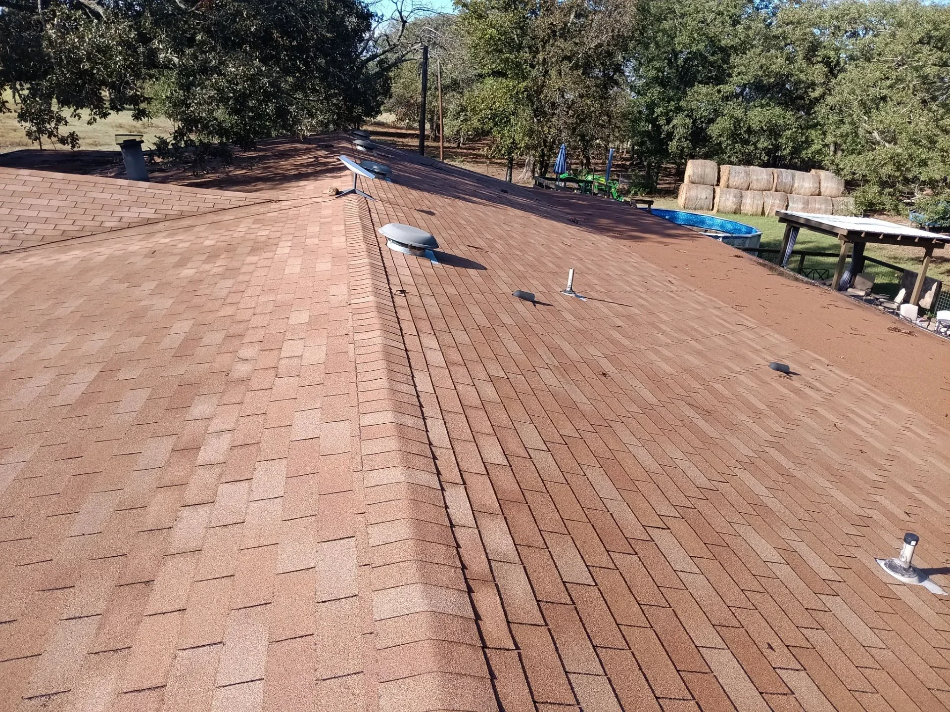 Newly installed terra cotta asphalt shingle roof with ventilation and flashing details