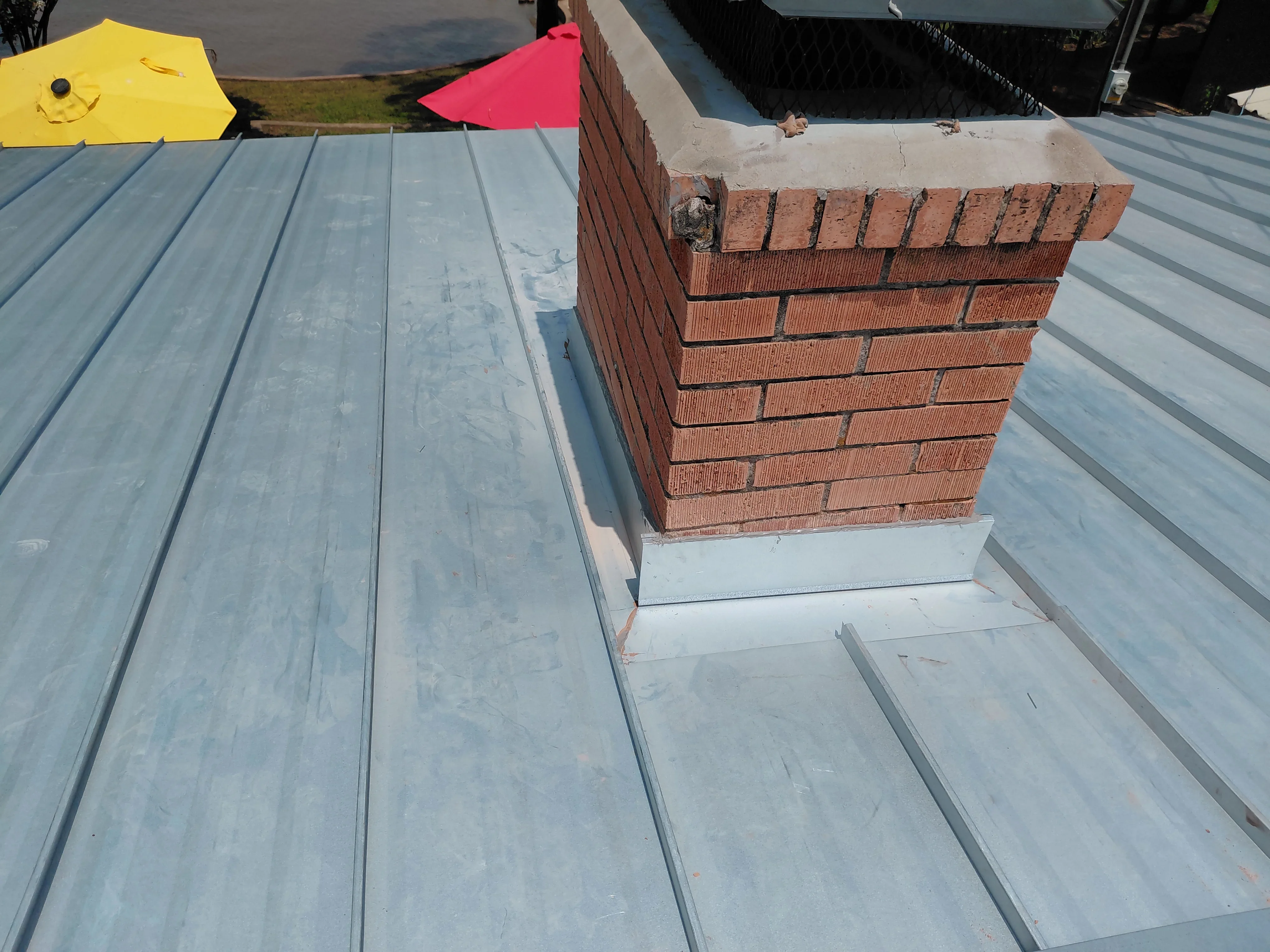 Standing seam metal roof with brick chimney and white flashing trim