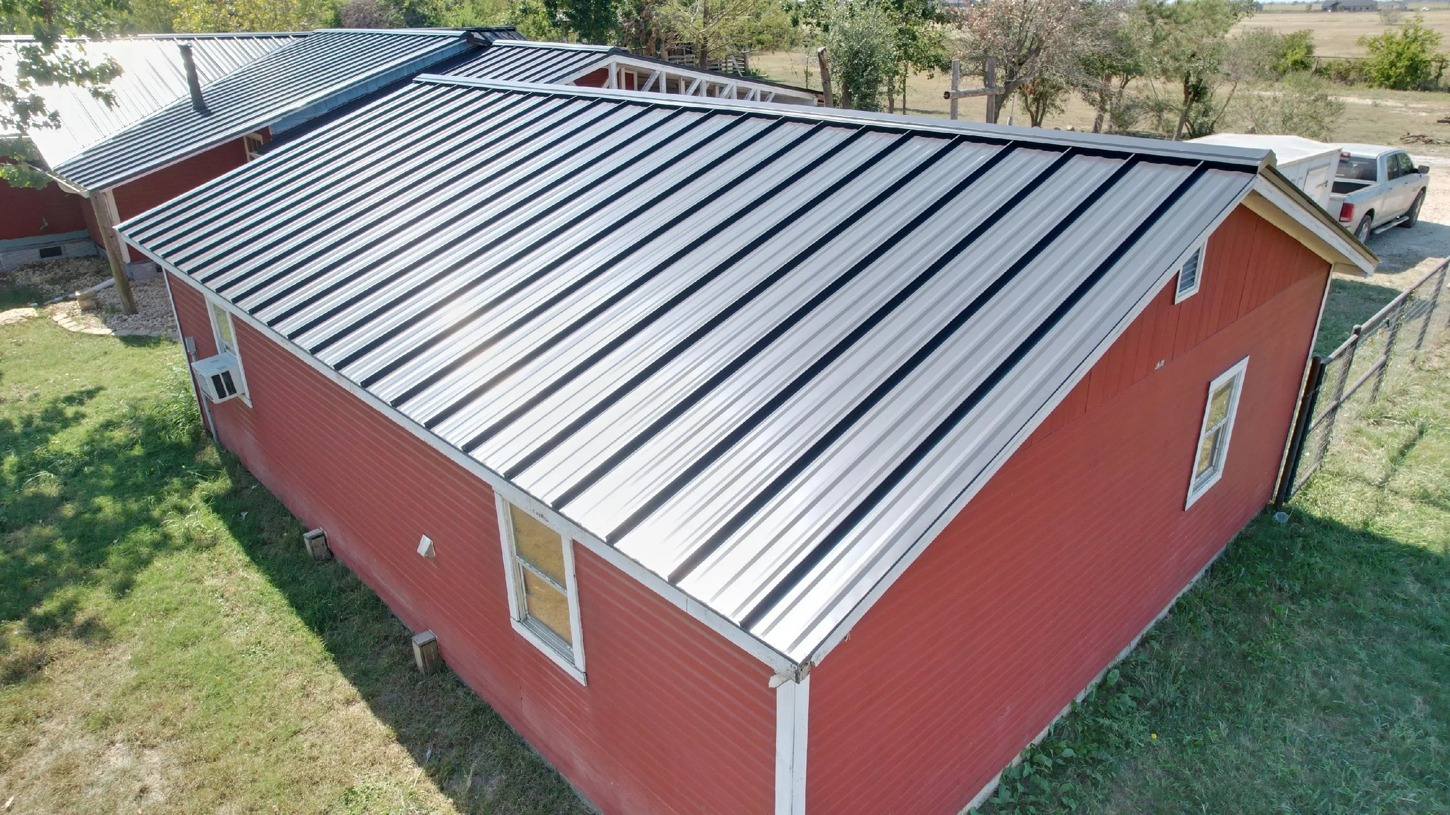 Standing seam metal roof with dark blue and silver panels on red agricultural building