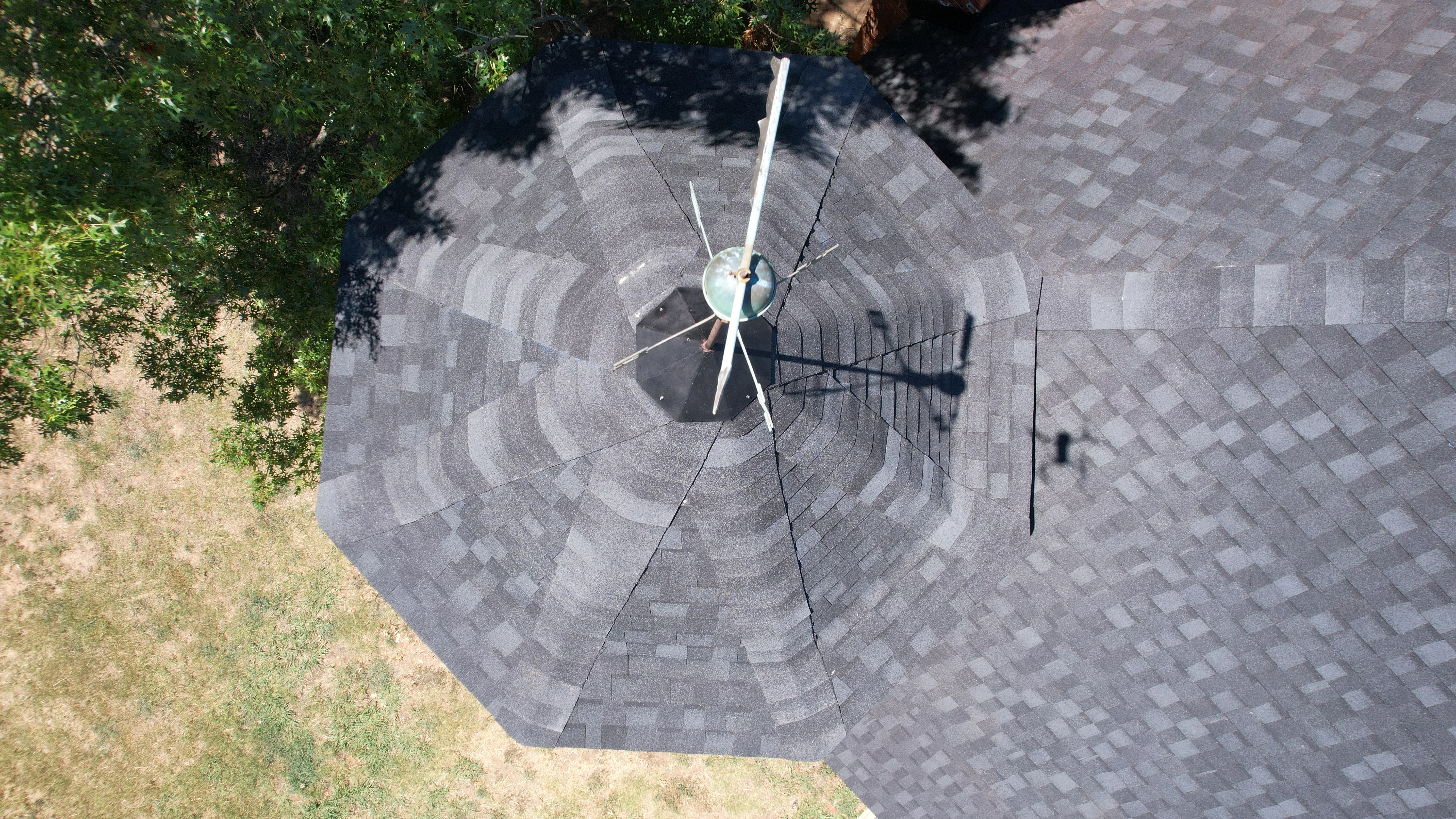 Aerial view of completed architectural asphalt shingle roof with multi-toned gray shingles and complex geometric design