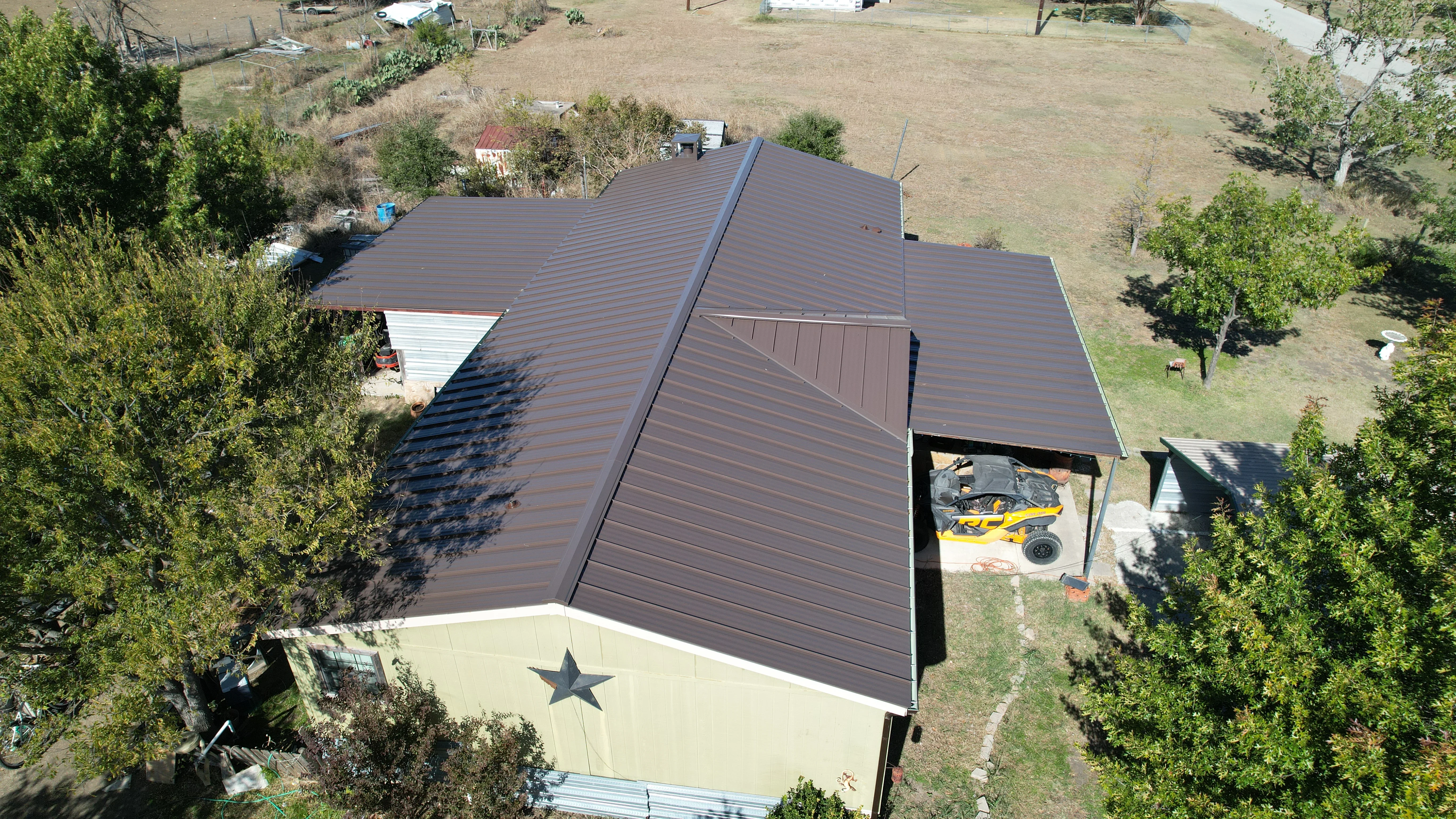 Dark brown metal standing seam roof installed on cream metal-sided building with multiple roof planes