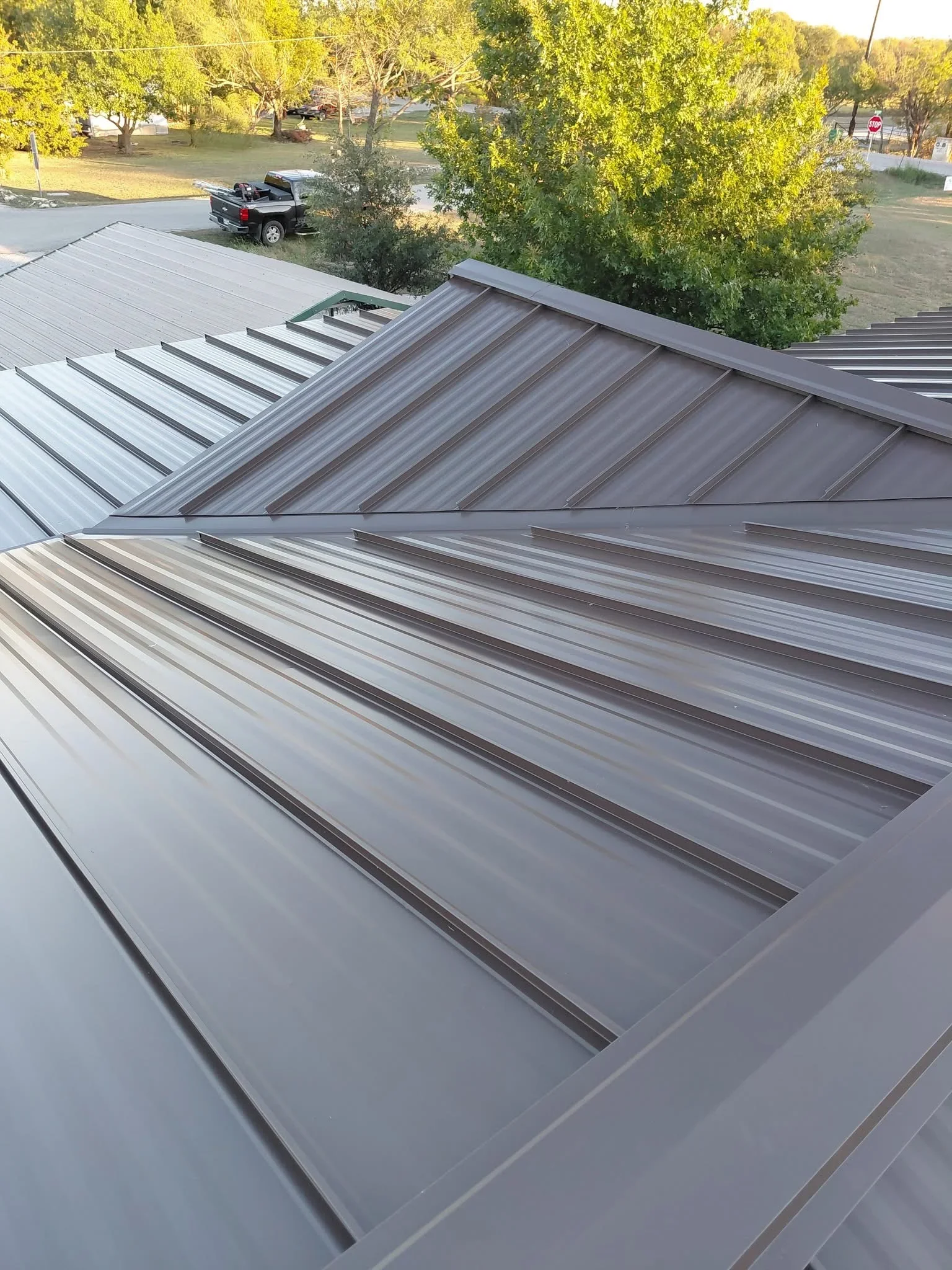 Standing seam metal roof with charcoal gray panels and vertical ribs installed on residential structure