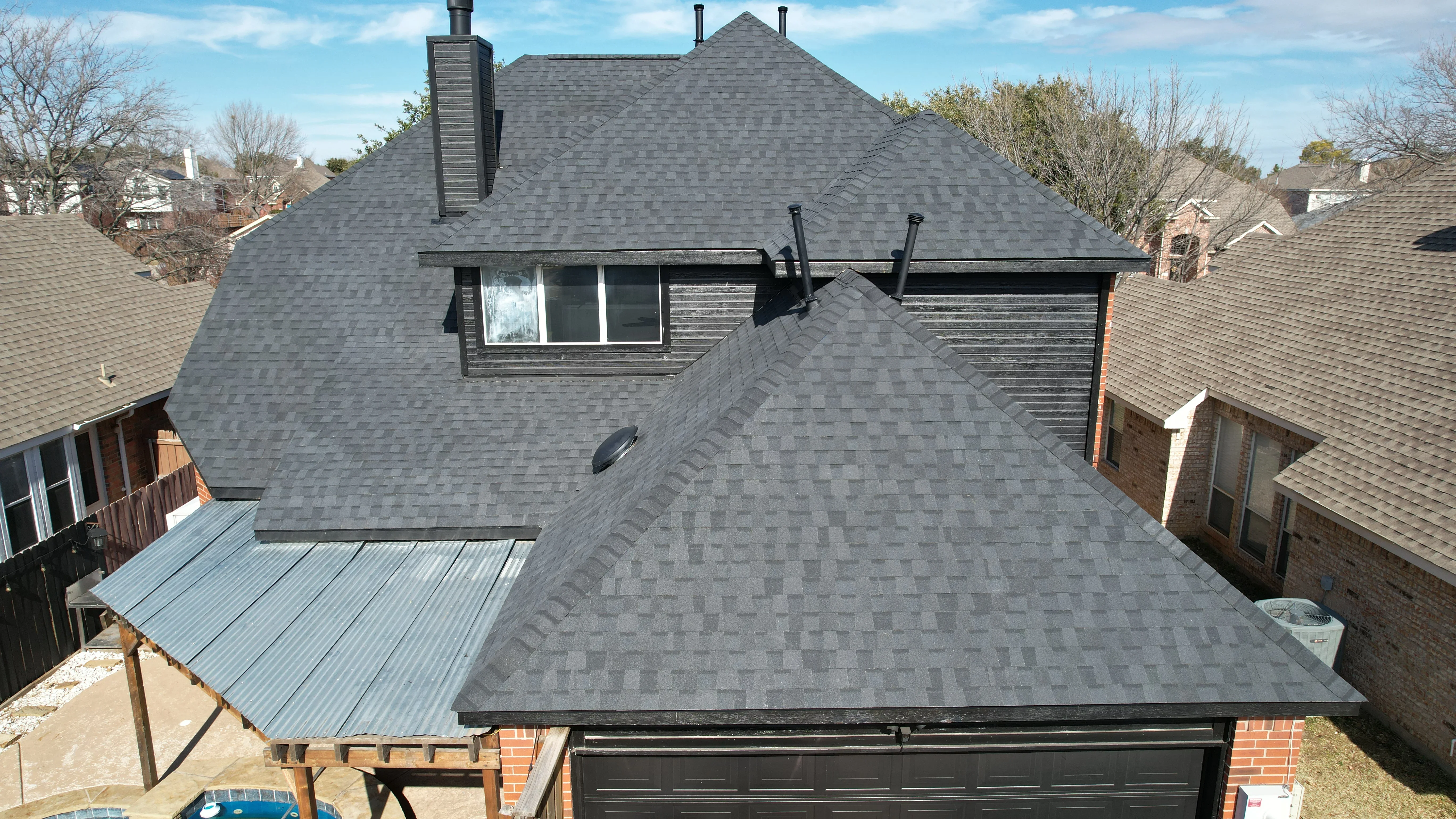 Charcoal gray architectural asphalt shingle roof with dormers, metal flashing, and black trim on residential home