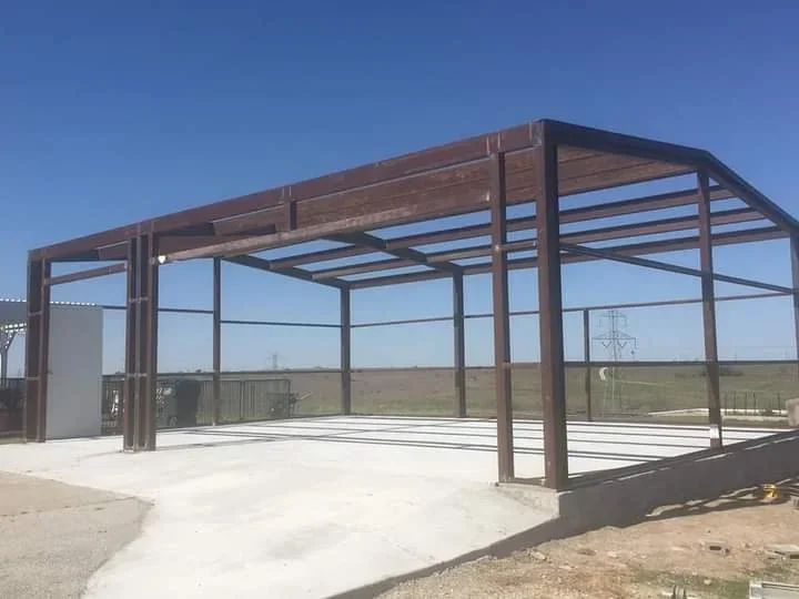 Steel frame structure with corrugated metal roof and concrete pad foundation