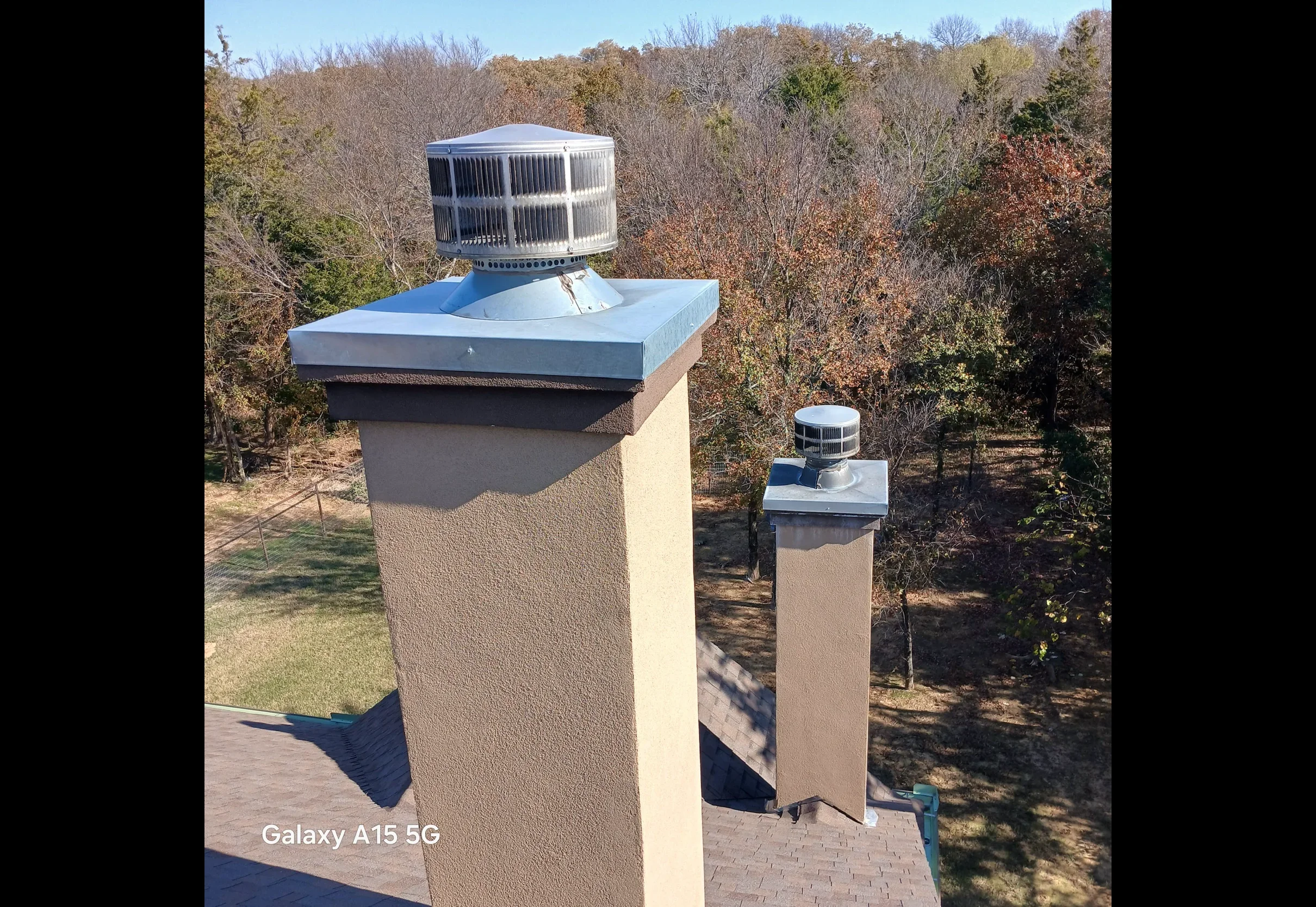 Galvanized steel chimney cap and roof vent with metal flashing on stucco chimney base