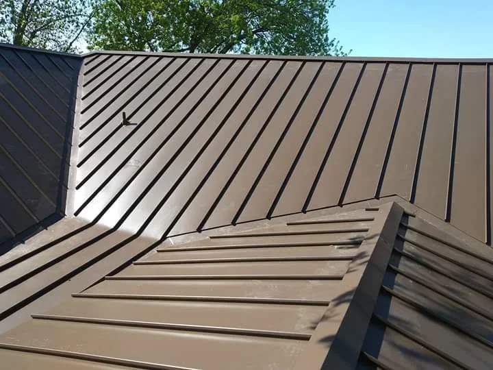 Standing seam metal roof with vertical ribs and valley transitions installed on residential structure