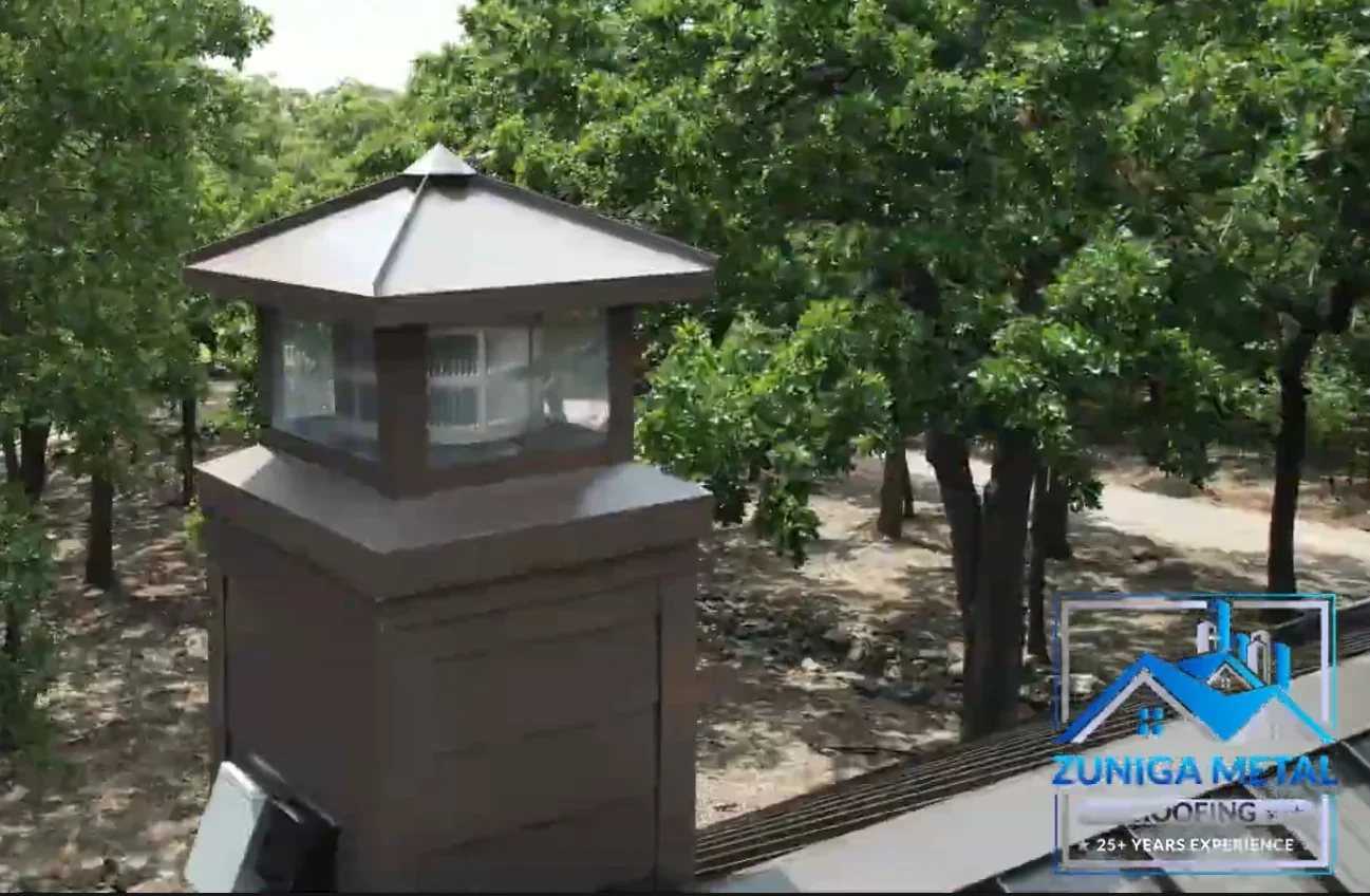 Dark metal chimney cap with pyramidal roof and white interior panels on residential chimney