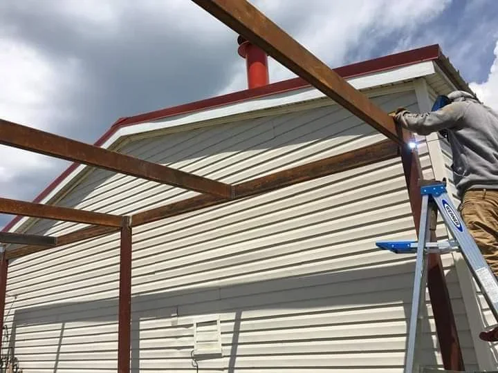 Metal roof installation with corrugated panels, wooden beams, and red trim accents