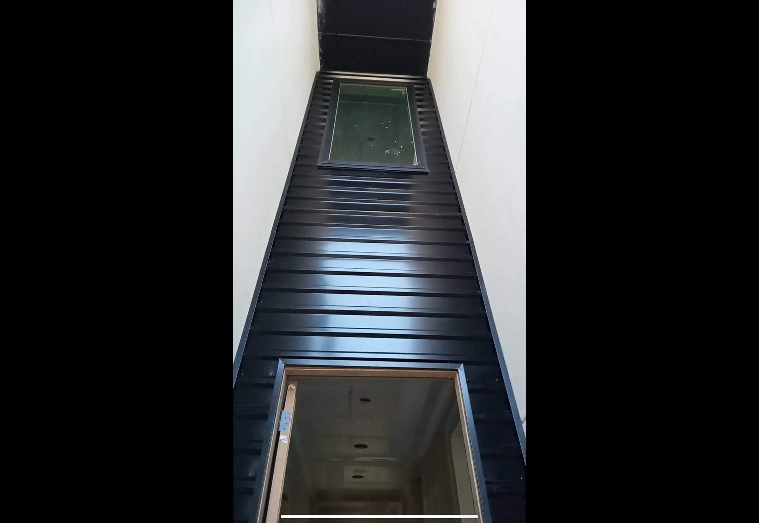 Black metal standing seam roof with two integrated skylights and clean flashing details
