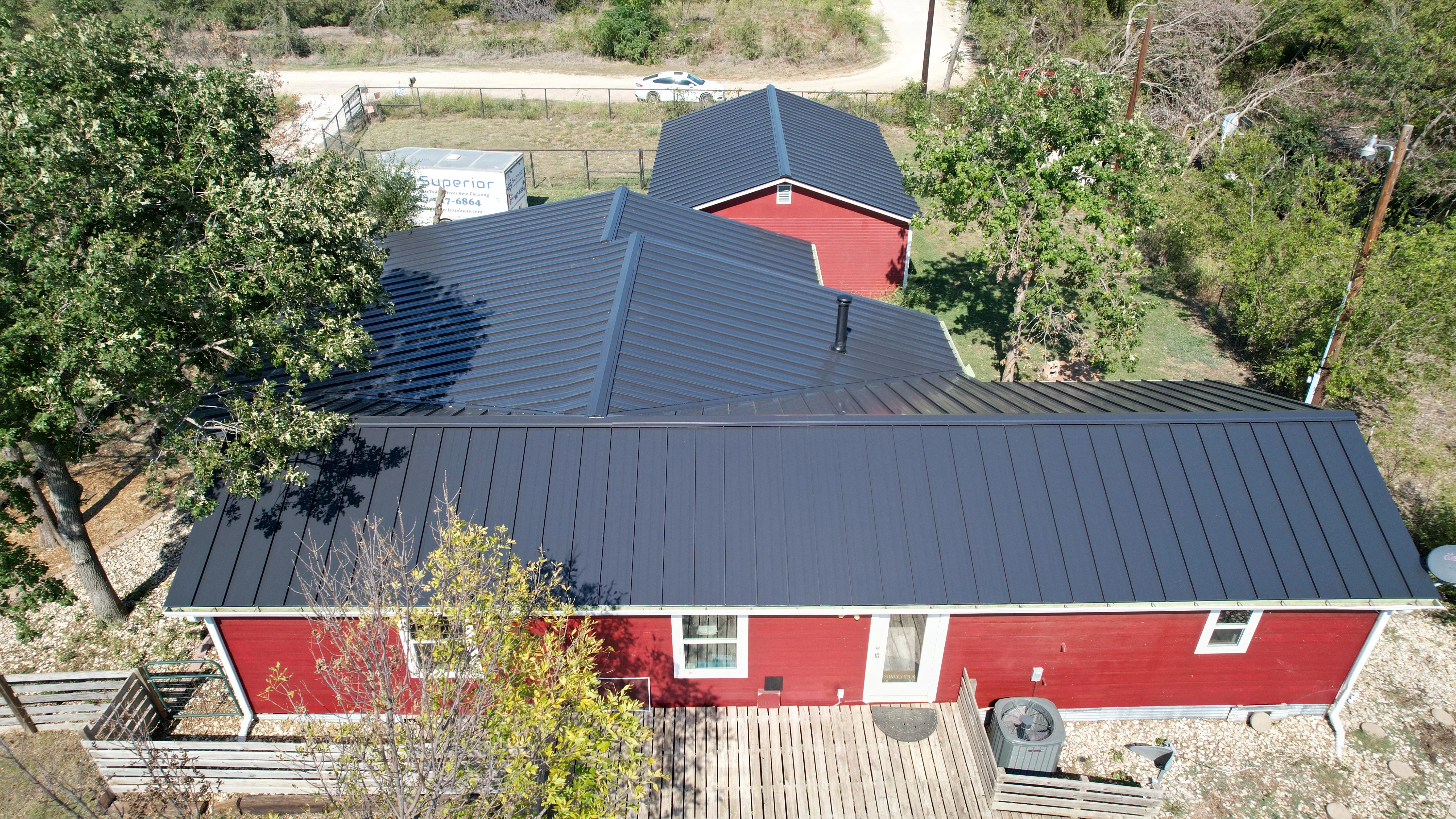 Dark gray standing seam metal roof with multiple planes and valleys on red residential home