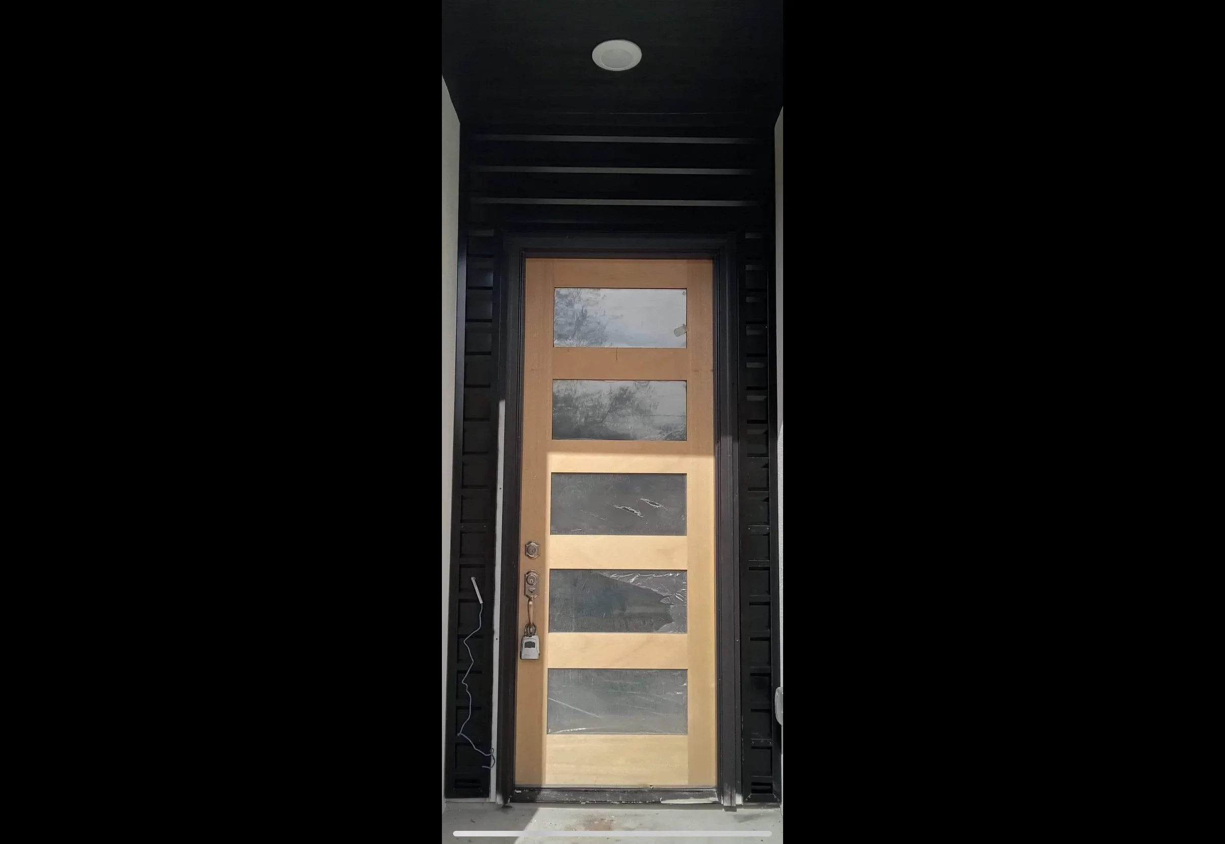 Wood entry door with five glass panels and modern hardware in dark metal frame