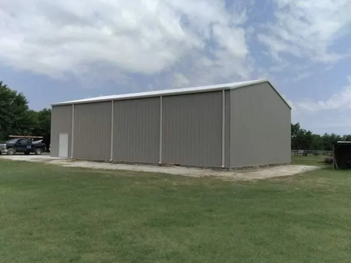 Corrugated metal building with pitched roof and vertical support columns on concrete foundation