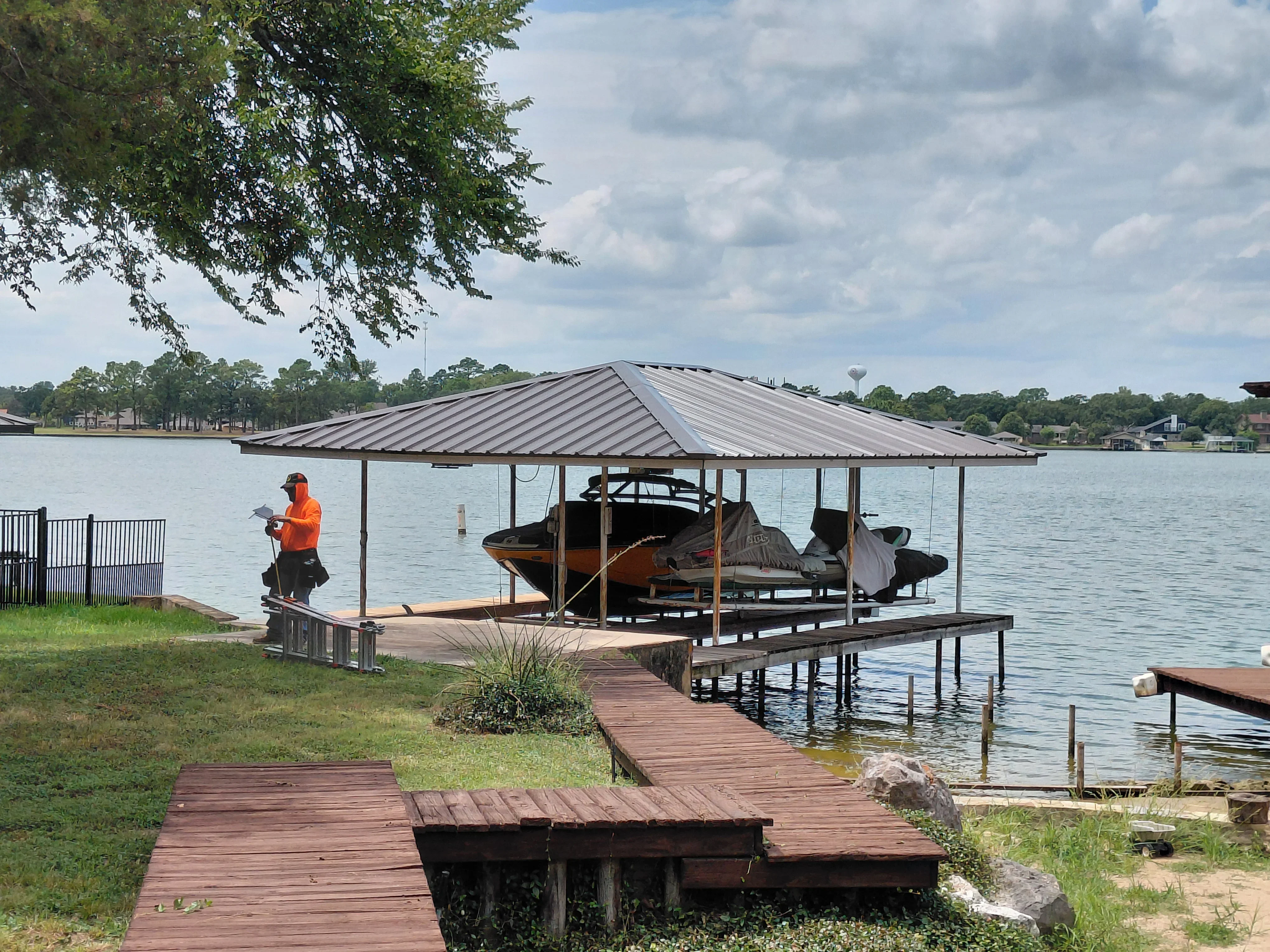 Standing seam metal roof over waterfront boat dock with wooden decking and support structure
