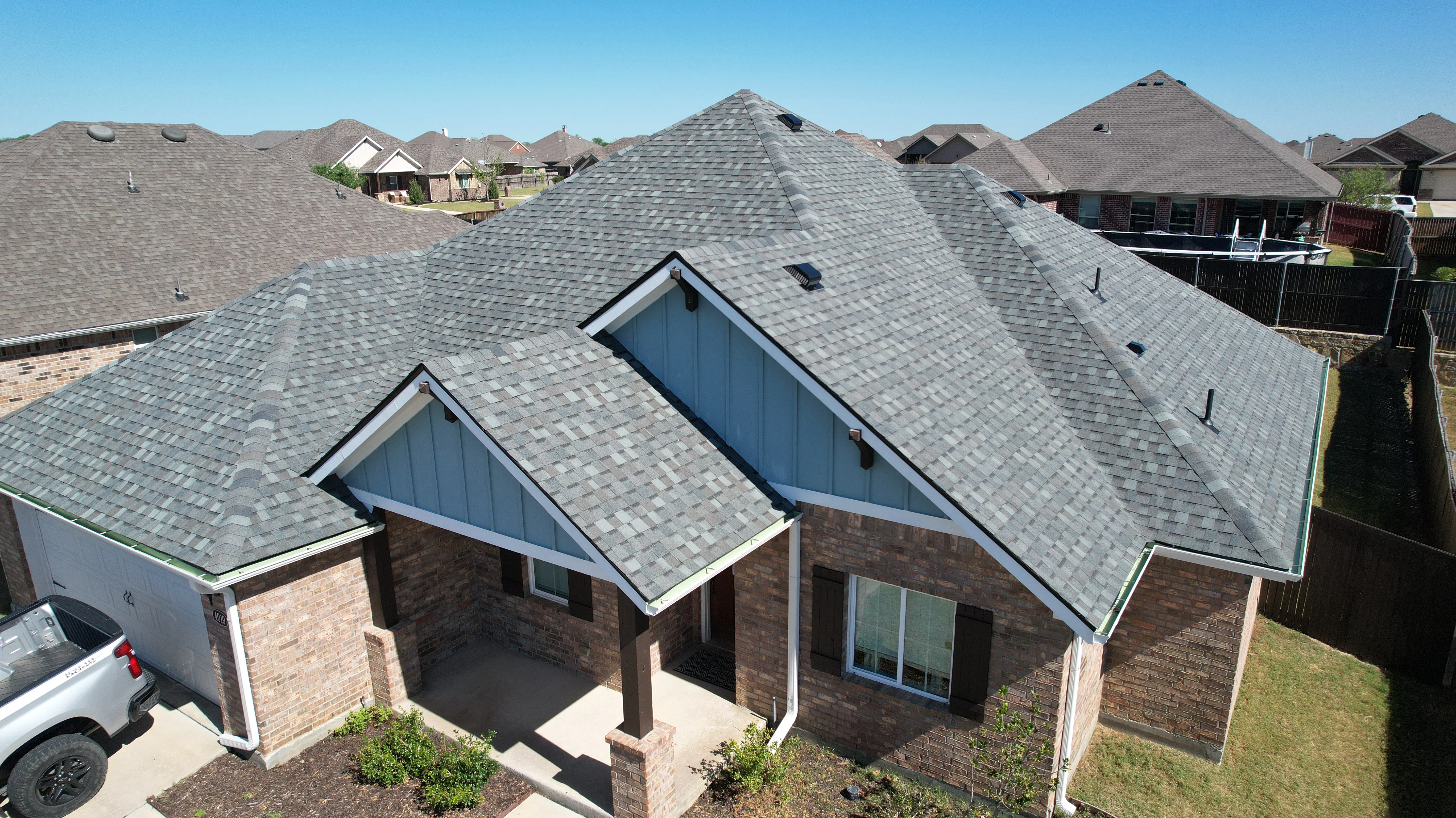 Gray architectural shingle roof with multiple peaks on brick home with gable vents