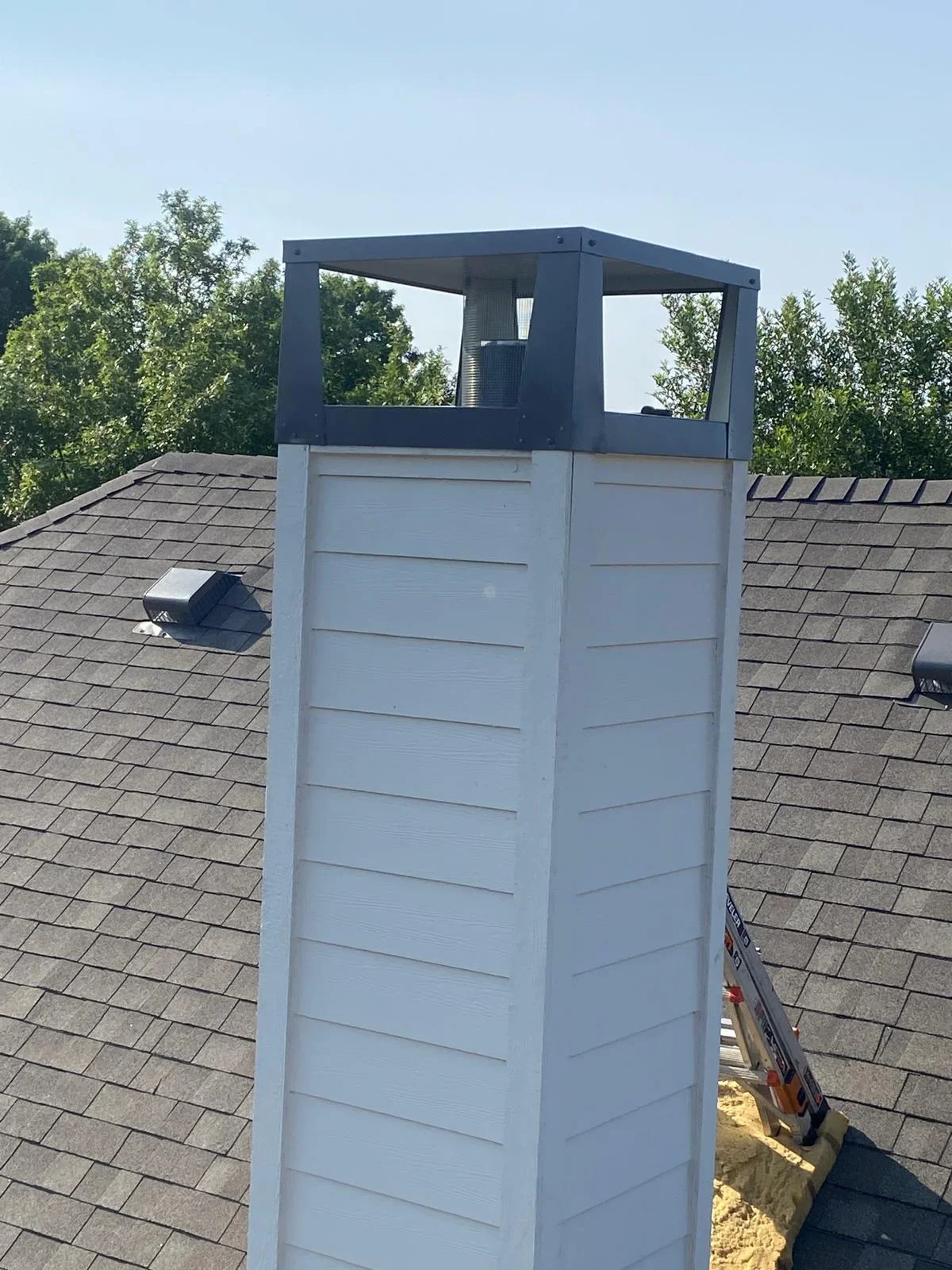 White PVC roof vent stack with black cap on asphalt shingle roof installation
